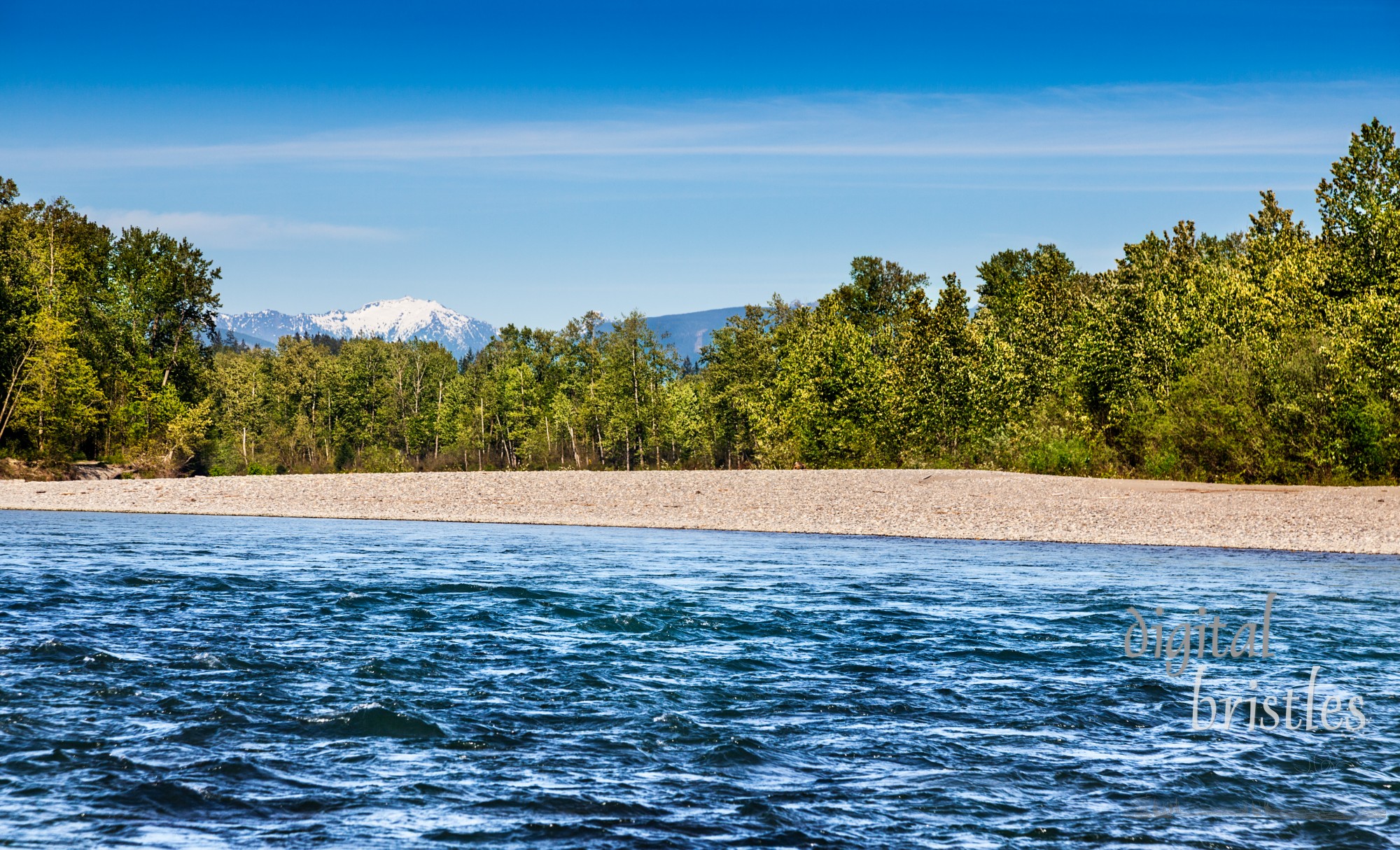 Swift current of the Skykomish River in Monroe, Washington with a sunny backdrop of the Cascades to the East