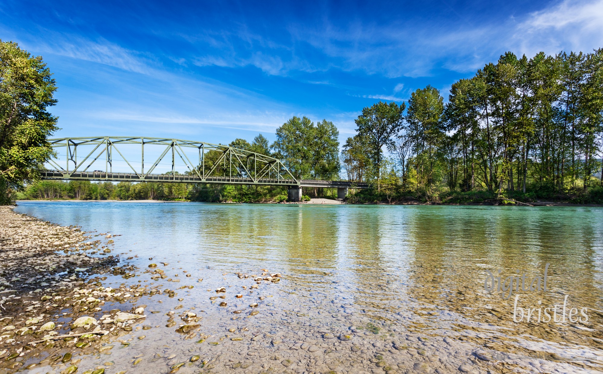 Calm Spring afternoon on the Skykomish River in Monroe, Washington by the Lewis Street bridge. The through truss bridge is state highway 203