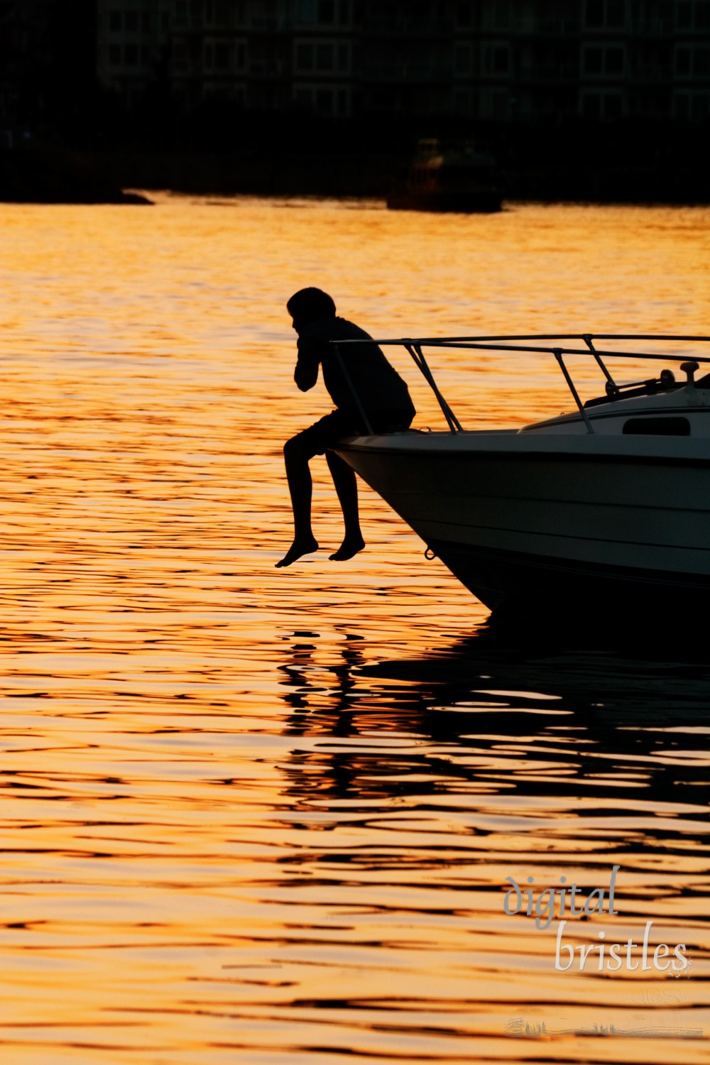 Boy hanging out in the prow of a boat at sunset, Victoria Harbour, BC