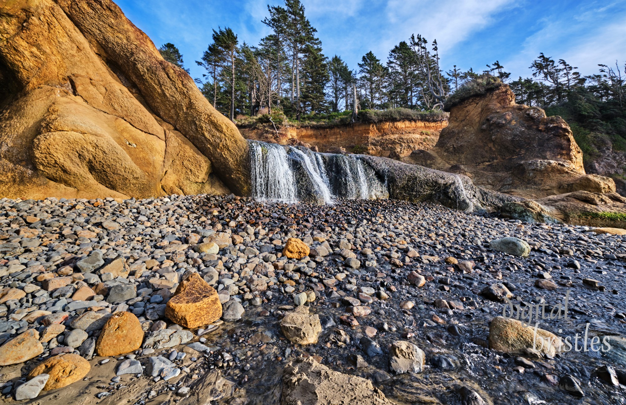 Waterfall carves through the rock and falls down the beach at Hug Point, Oregon