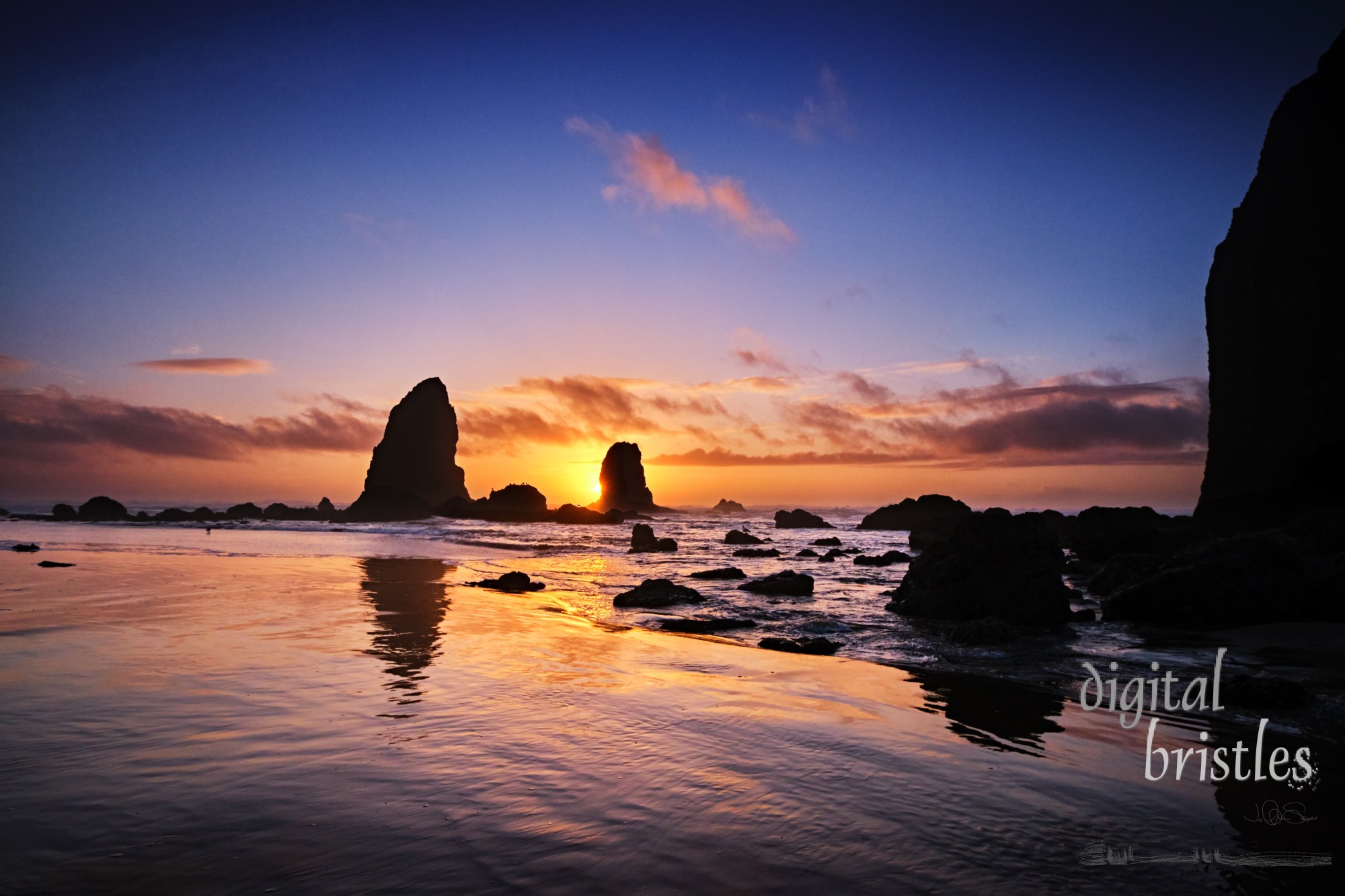 Sun about to set behind The Needles as tide pools around Haystack Rock fill with water as the tide comes in