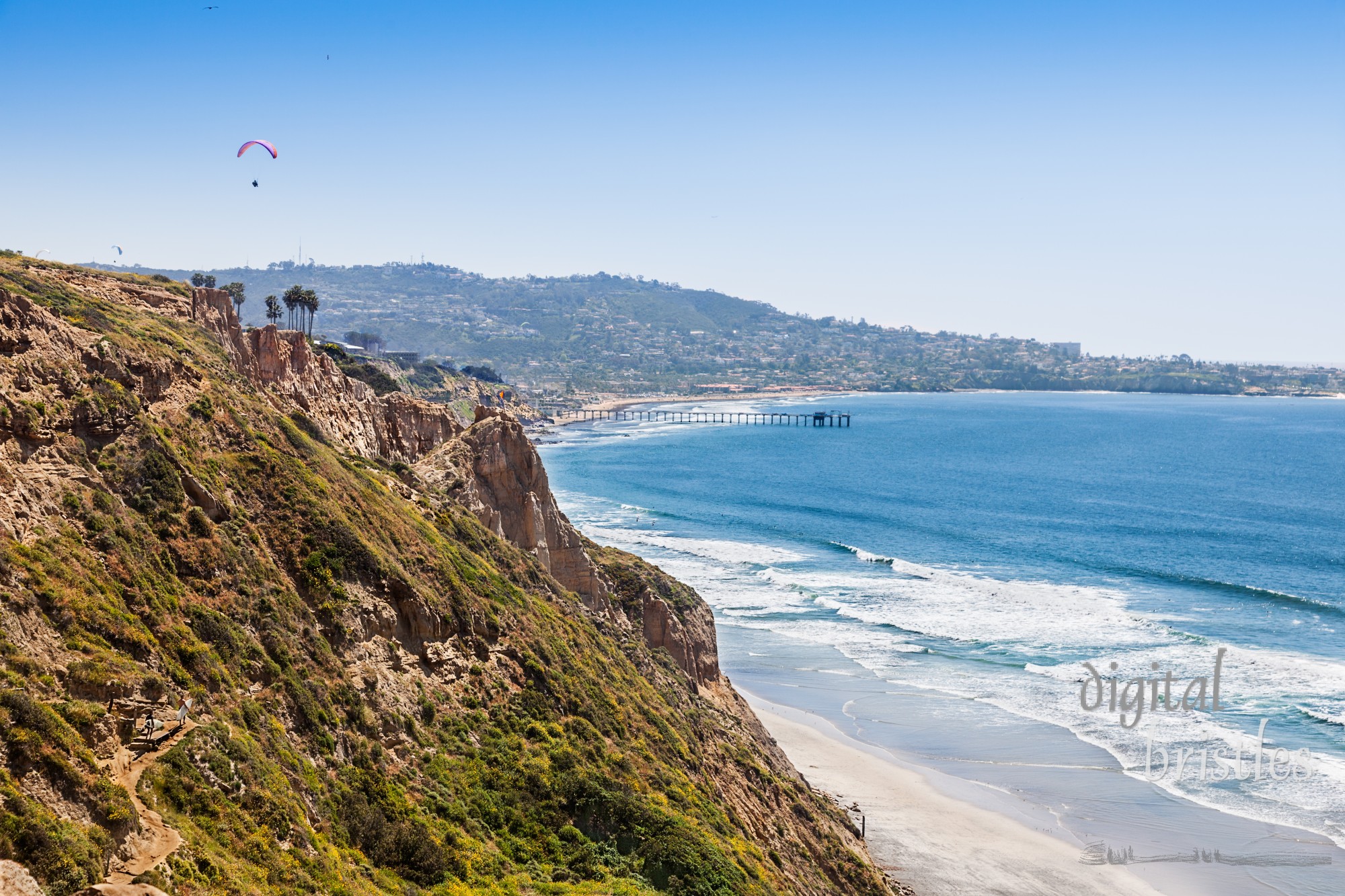 Surfers climb the steep path from the beach up the cliffs at Torrey Pines. Scripps Pier, La Jolla Shores and La Jolla Cove in the distance