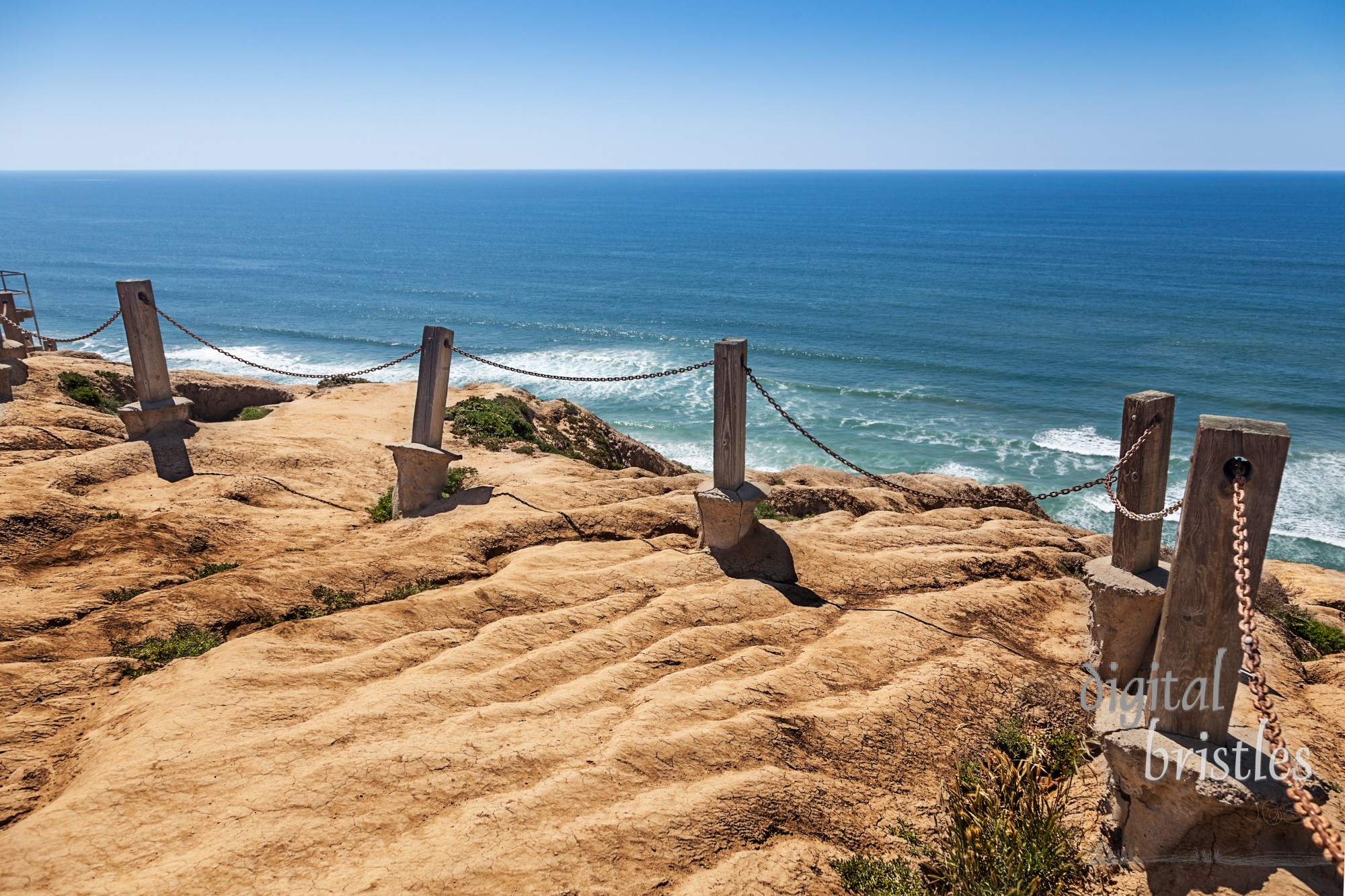 Cliff erosion damaging safety barrier posts and chain on the cliff edge at Torrey Pines, California