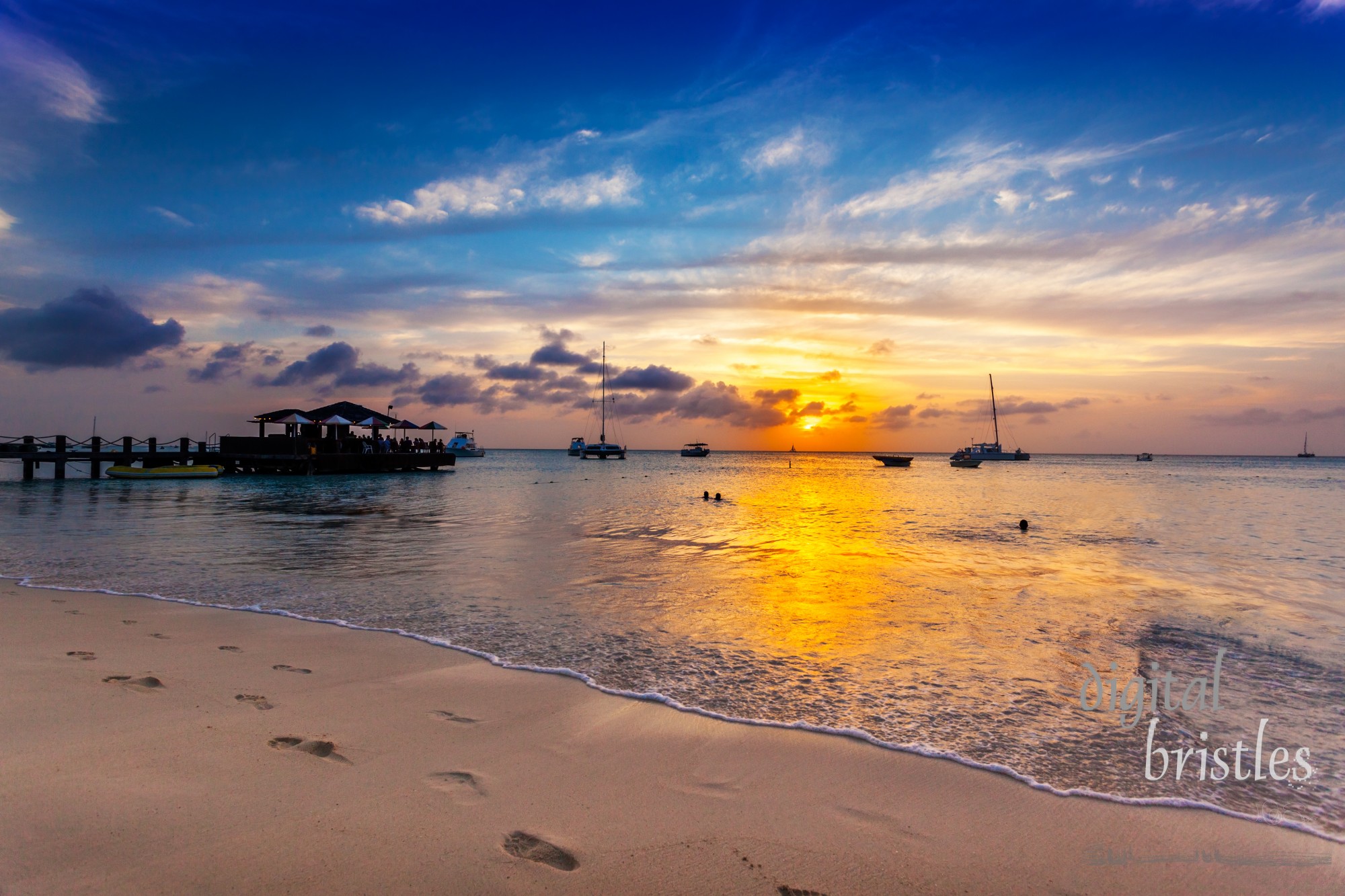 Boats, diners and swimmers enjoying sunset over Palm Beach, Aruba