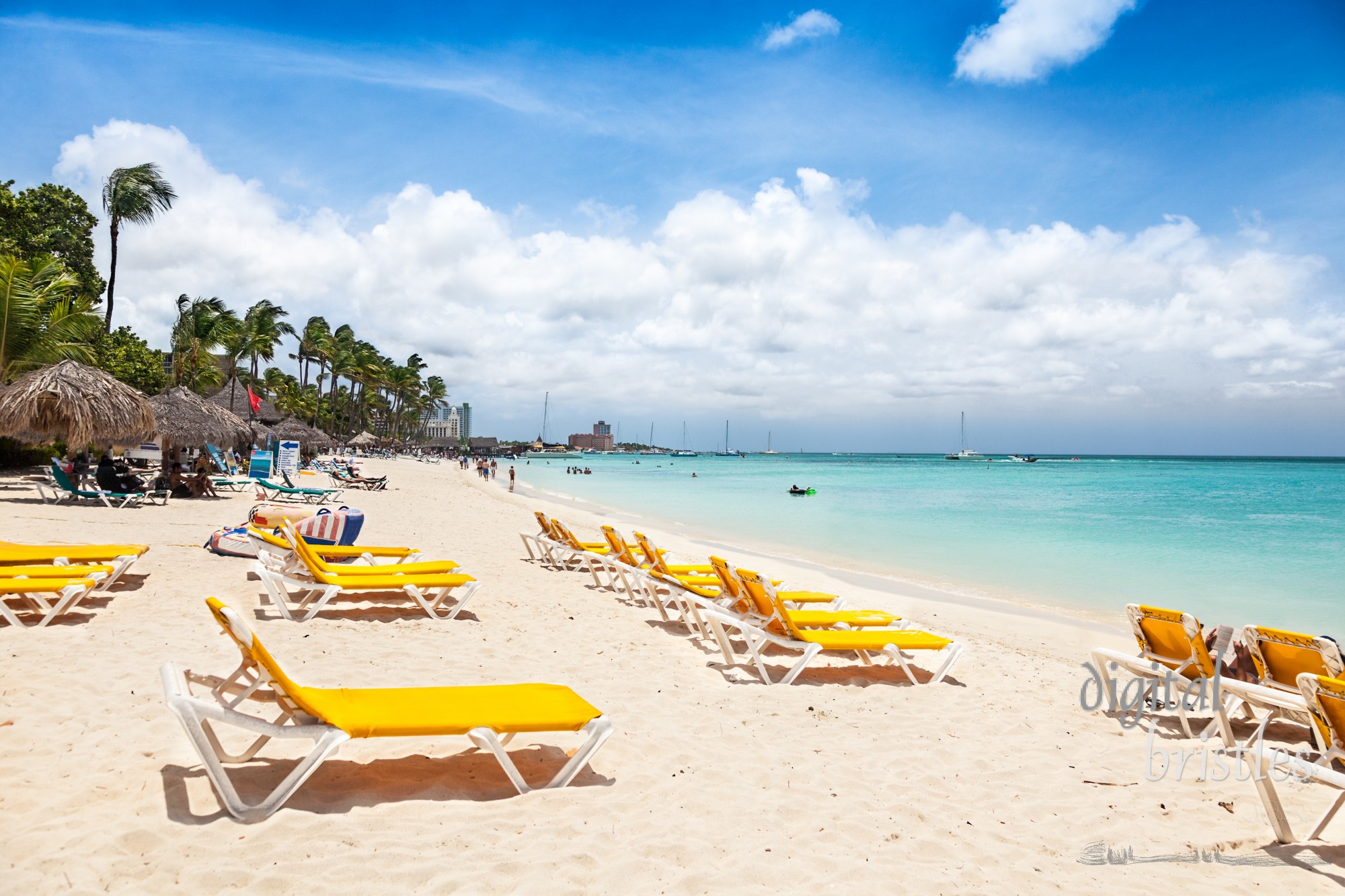 Aruba's busy Palm Beach with chairs, palapas and many tourists