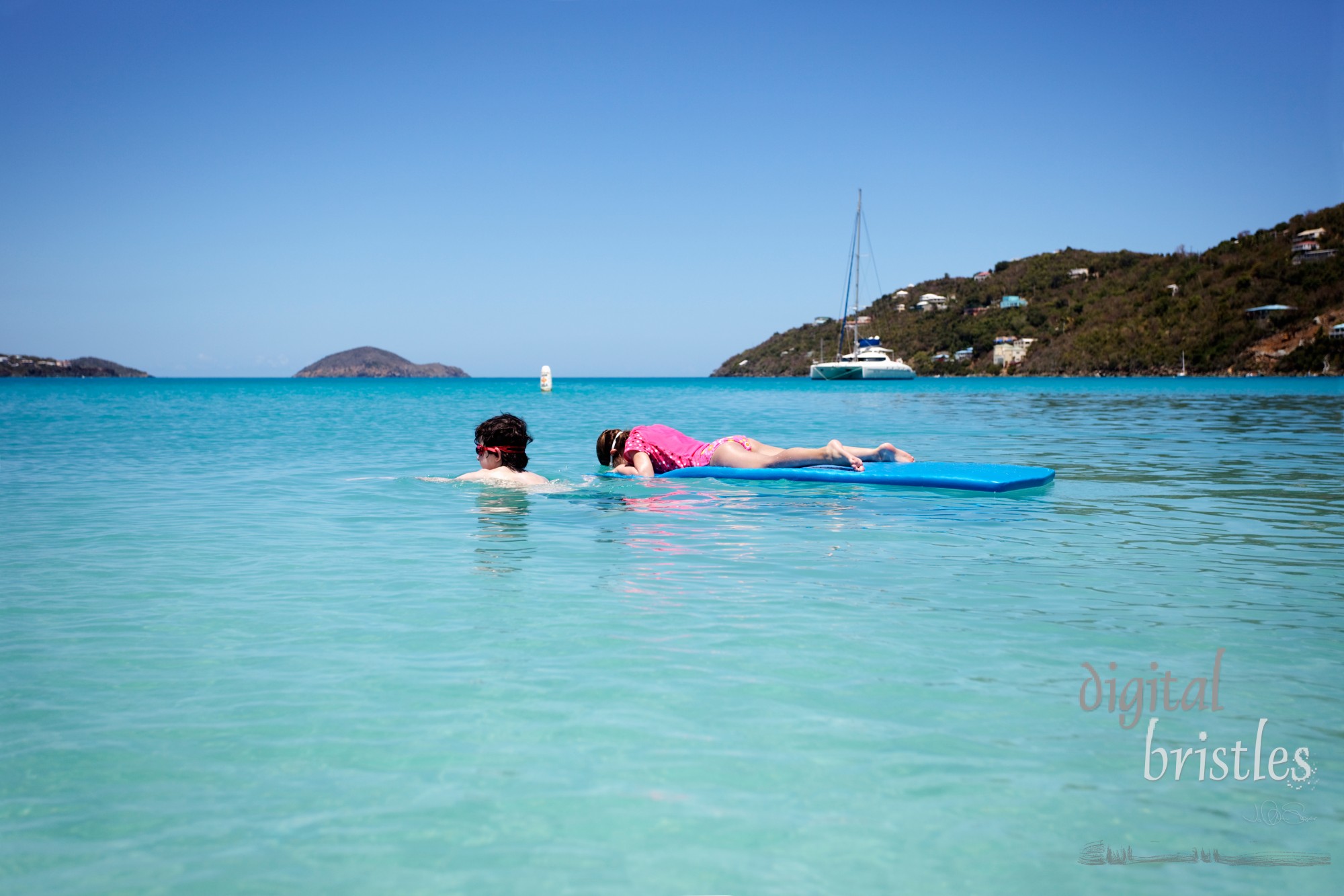 Big brother tows his sister while she looks at fish in a tropical bay