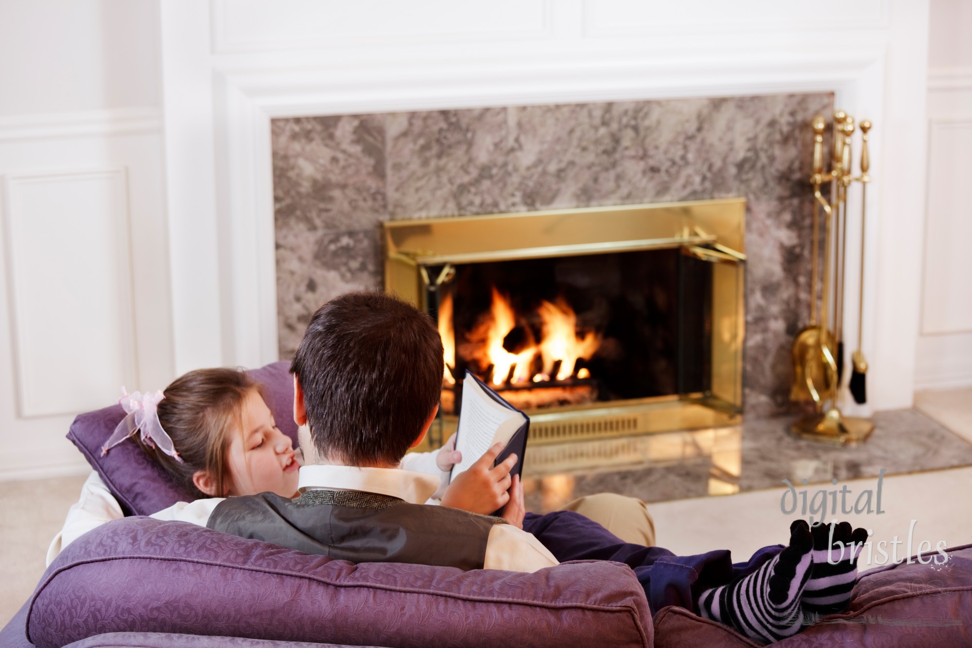 Father and daughter sit and read by the fire