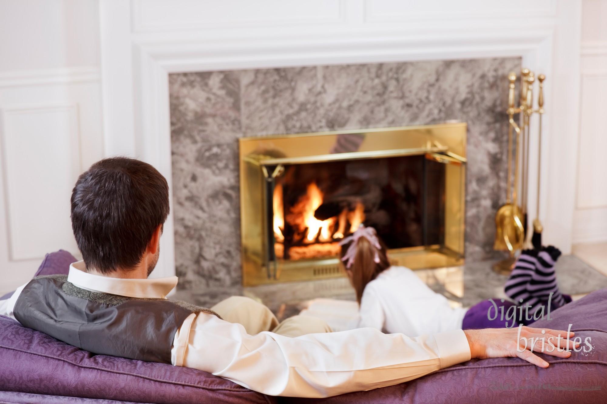 Dad sits and relaxes as his daughter reads by the fire