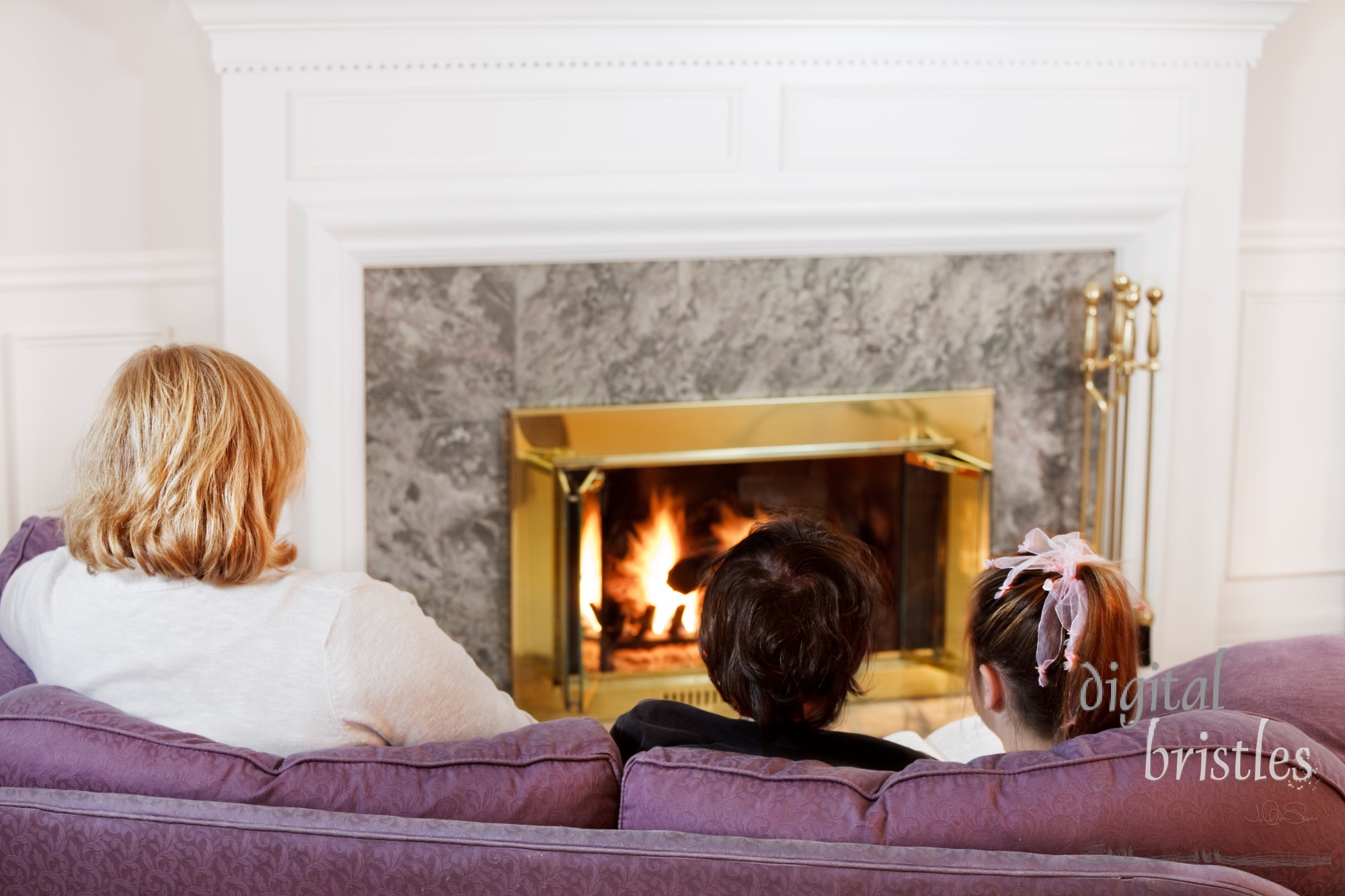 Mother son and daughter sit on the sofa  to read by the fire