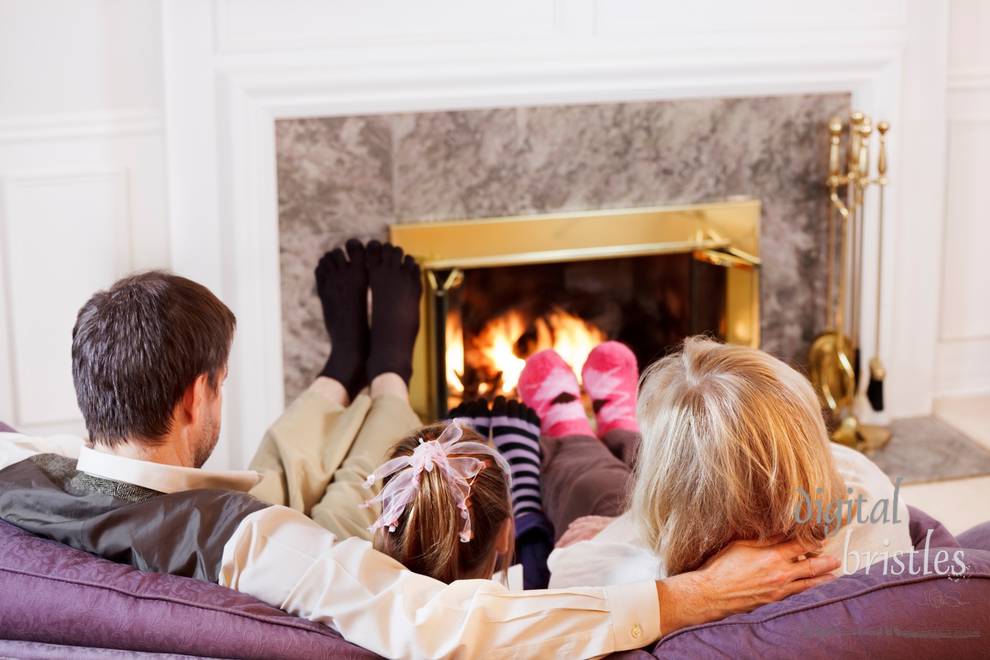 Mom, Dad and daughter warm their socked feet by the fire