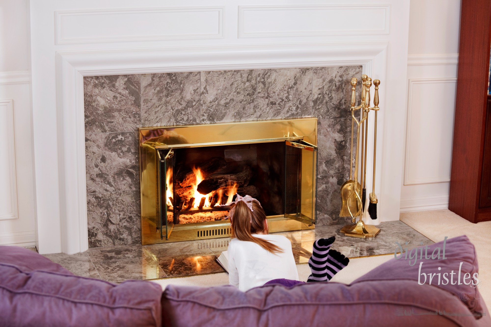 Young girl lies on the floor by the fire, reading