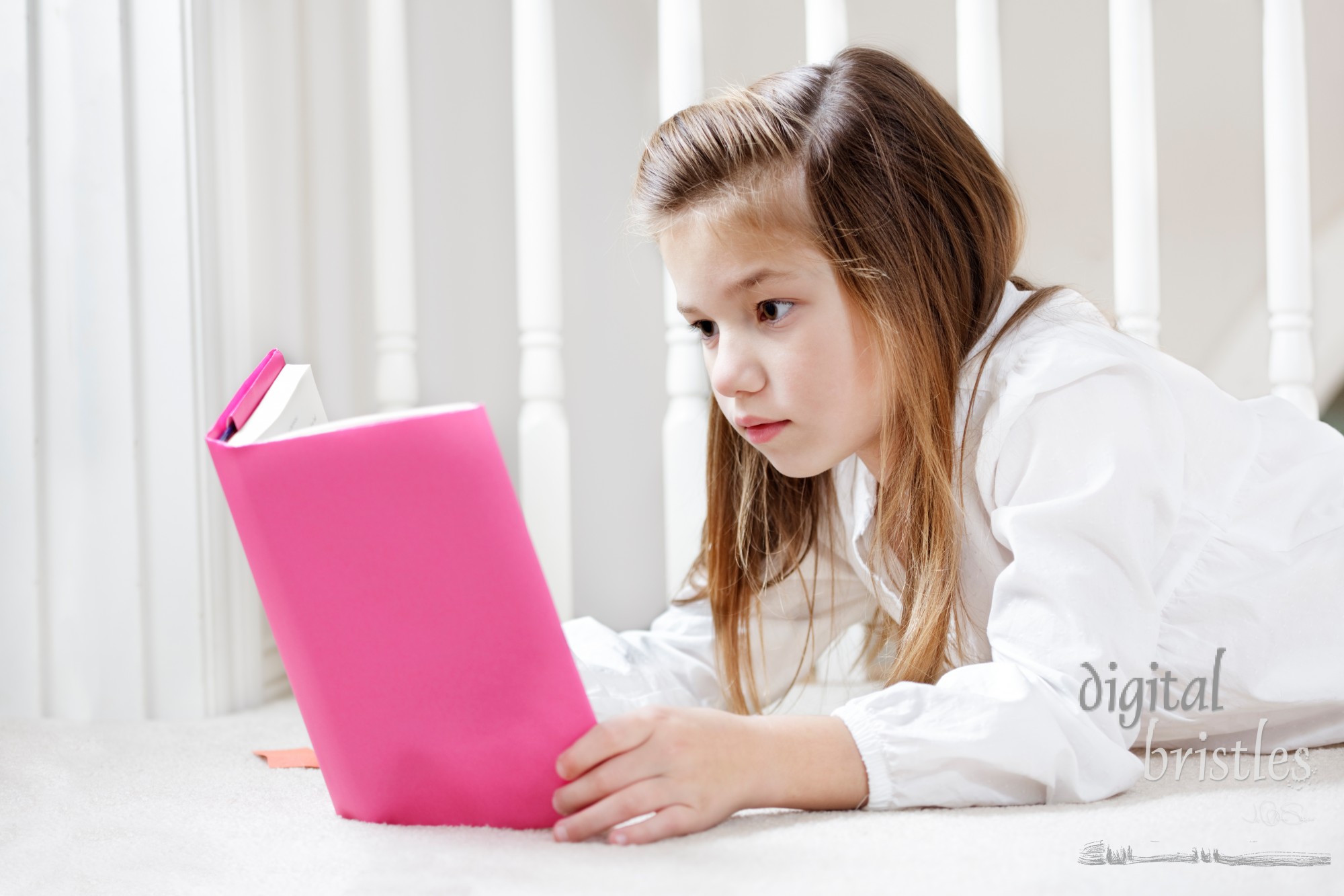 Young girl lying on the floor concentrating on her reading