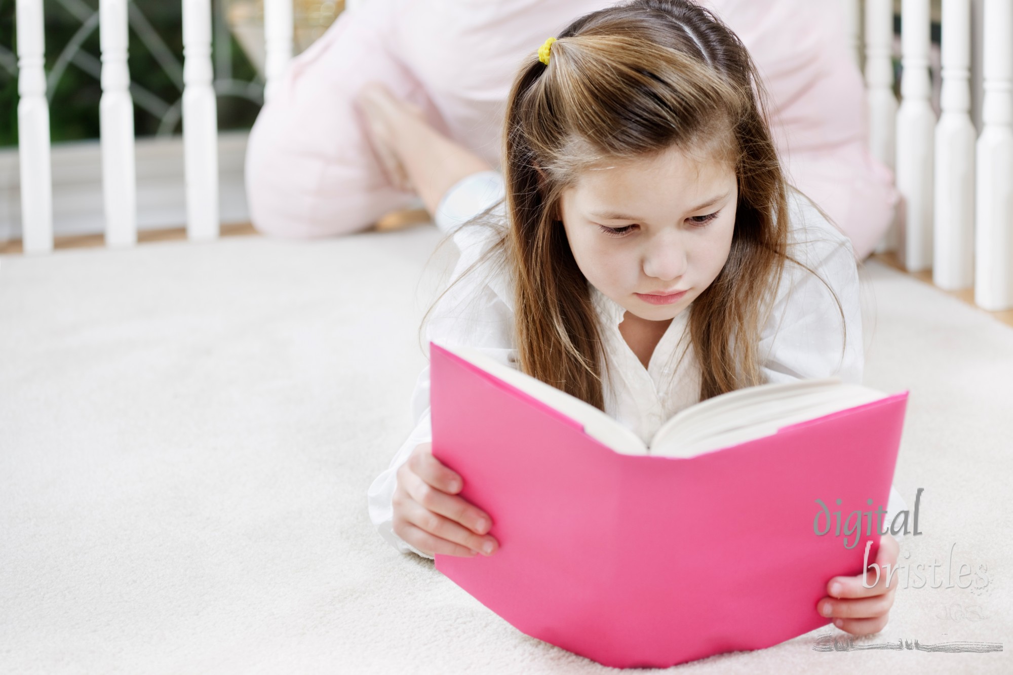 Young girl lying on the floor concentrating on her reading