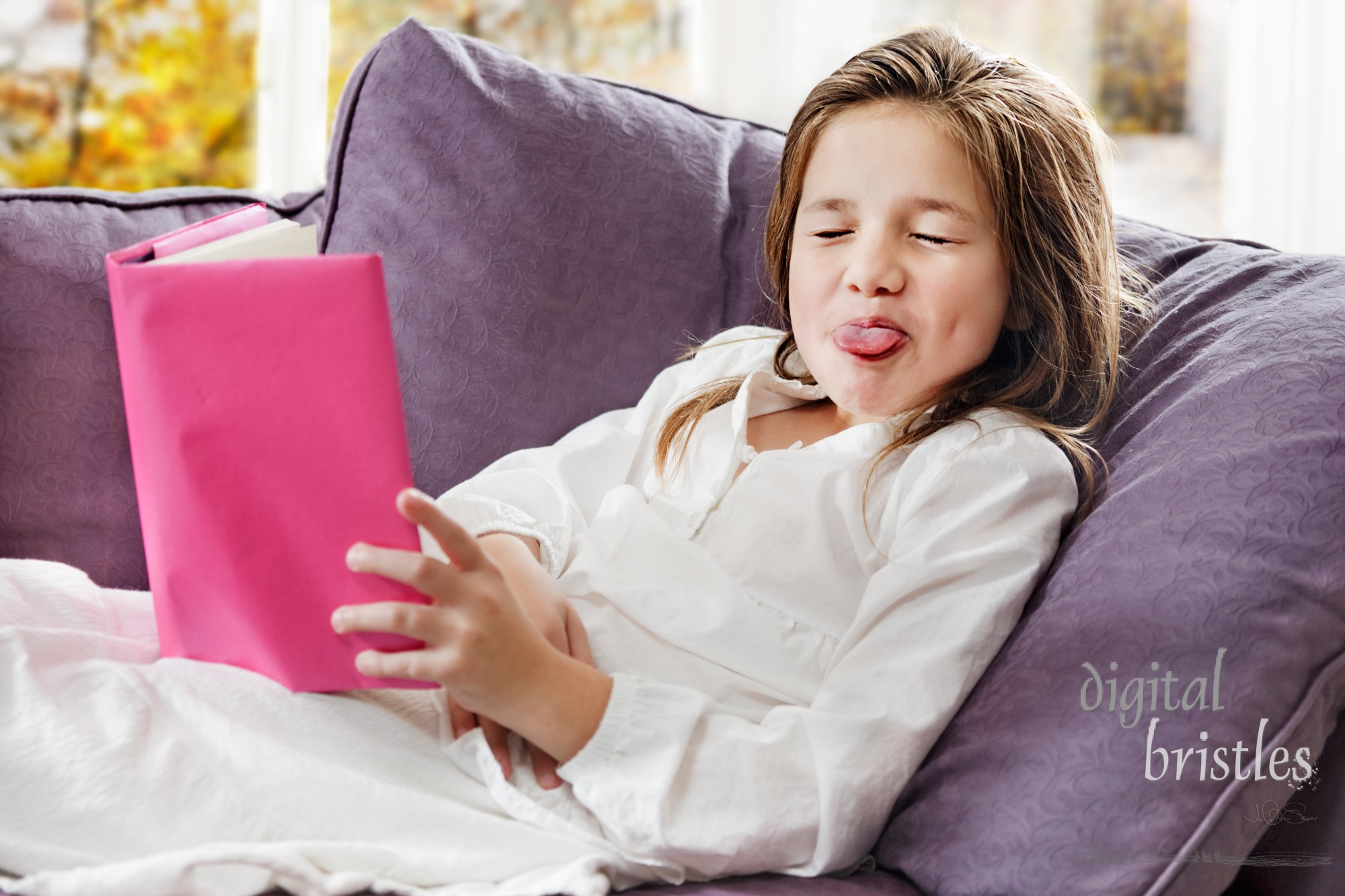 Young girl stops homework reading to stick her tongue out