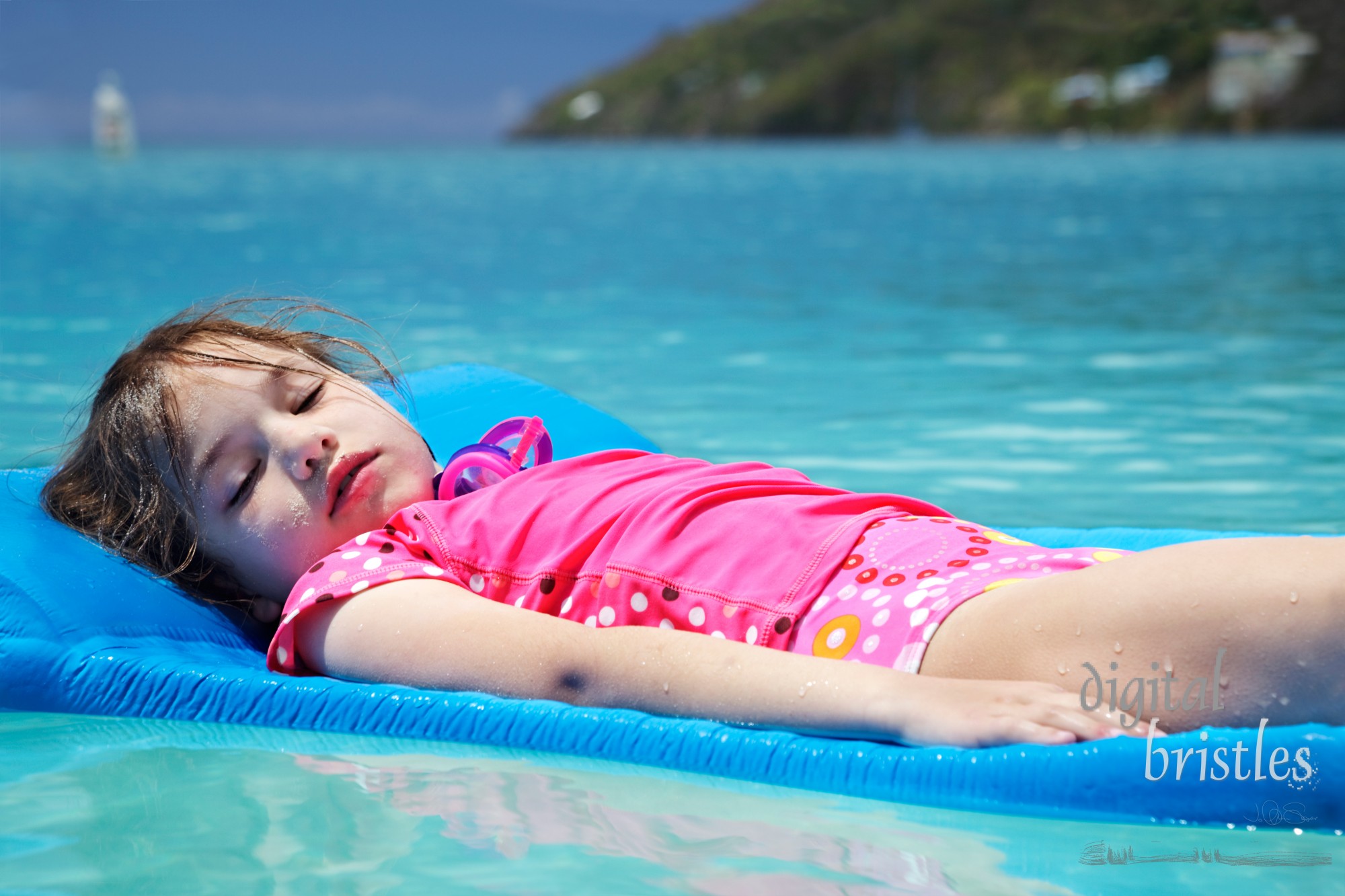 Young girl, eyes closed & covered in sand, floating peacefully in Magens Bay