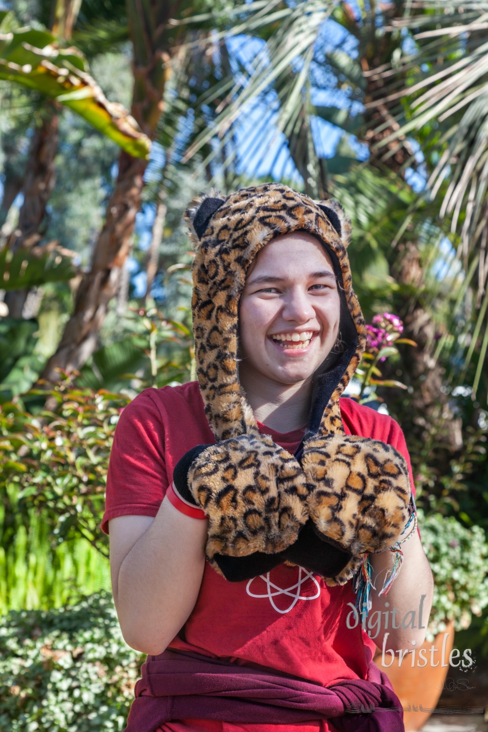 Happy teenage girl playfully posing in an animal print hat on a sunny Spring afternoon