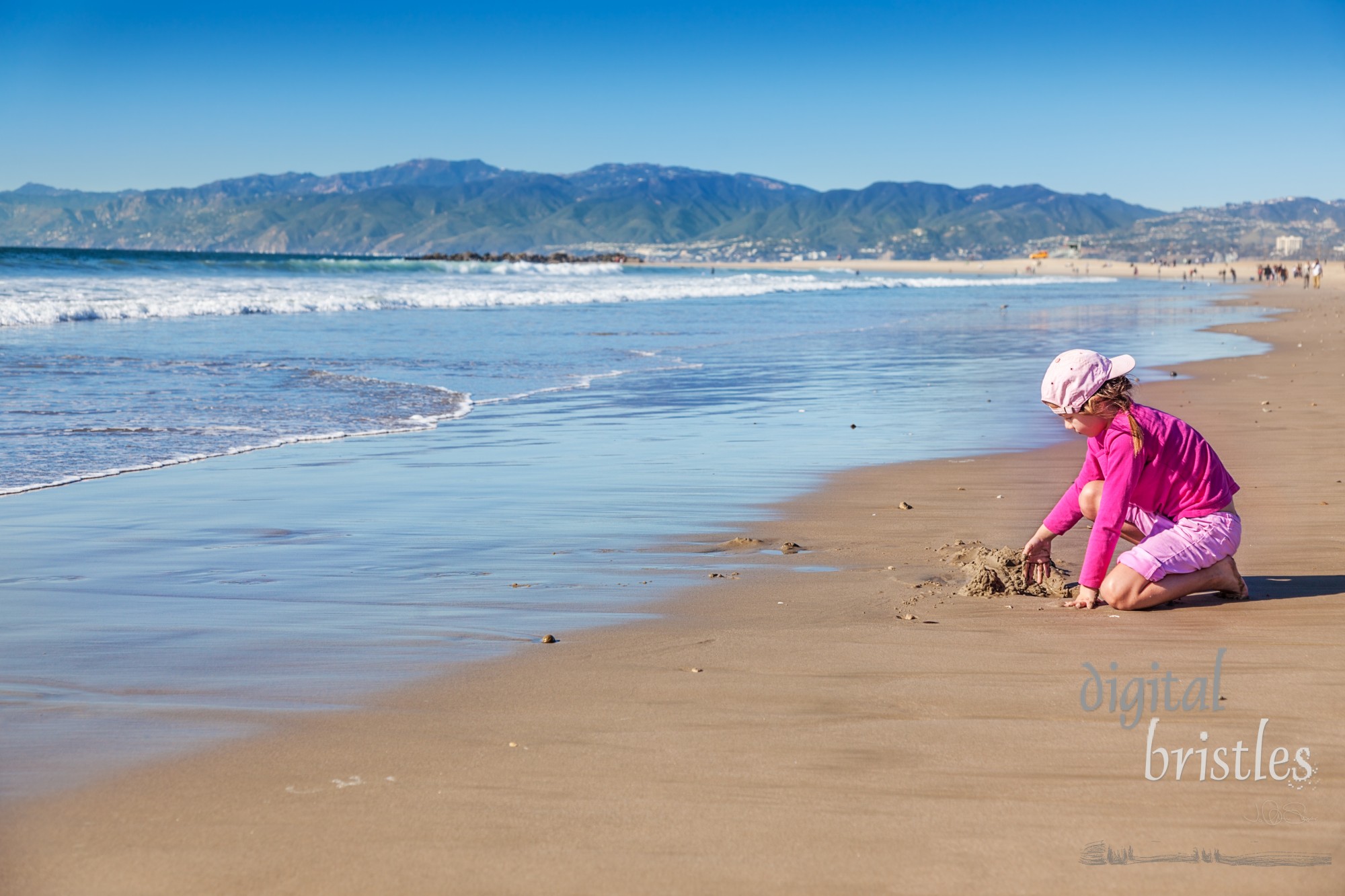 Young girl plays at water's edge on a sunny winter day at Venice Beach, California