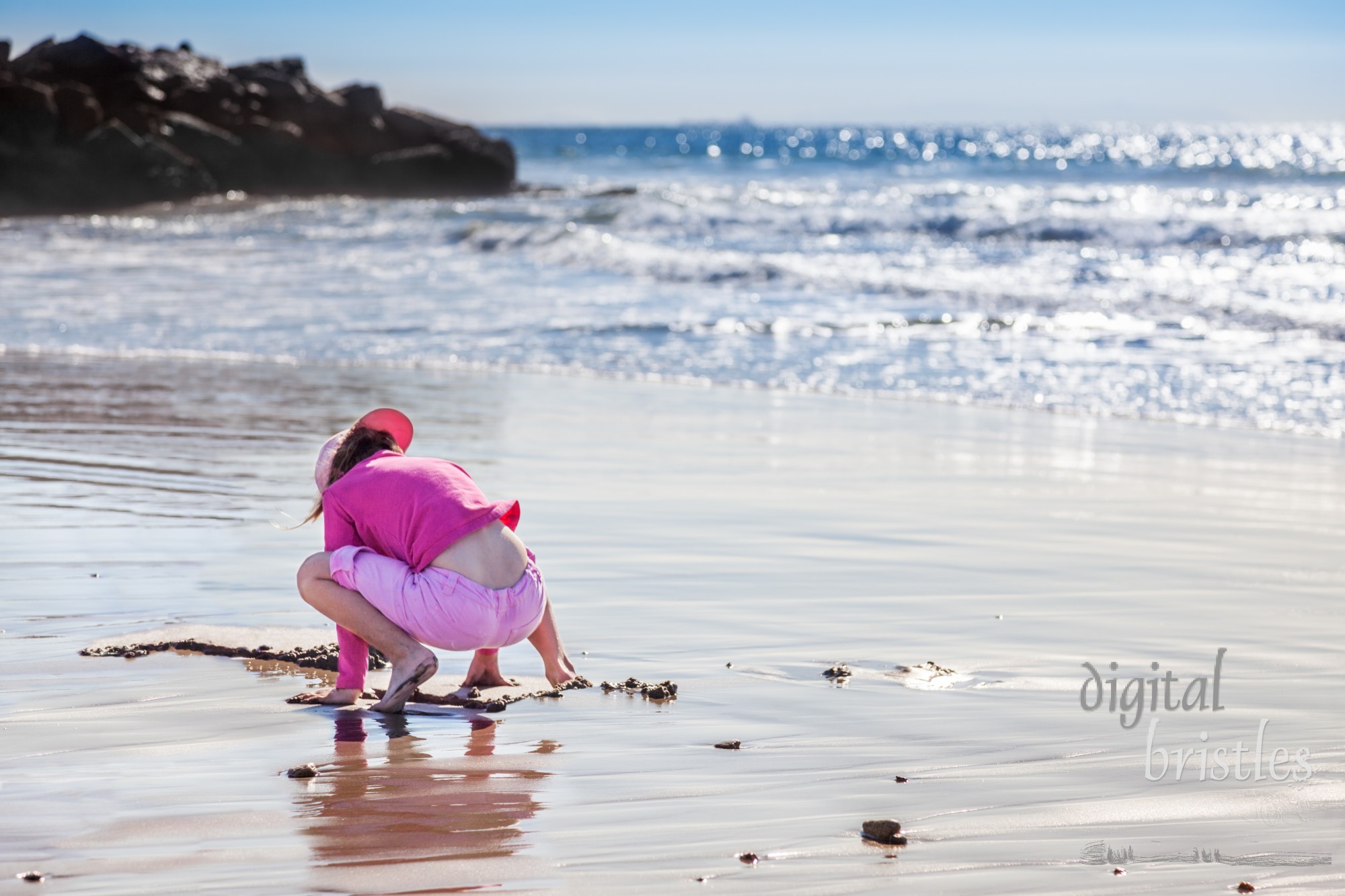 Little girl plays in the wet sand on Venice Beach on Christmas Day