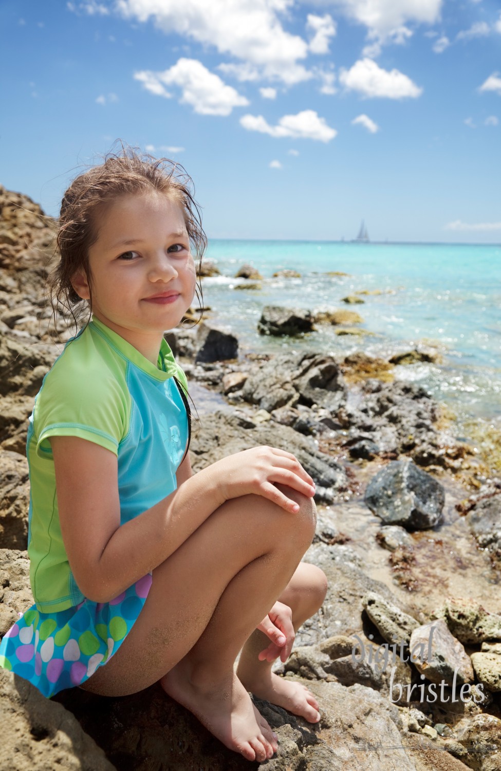 Young girl sitting on the rocks at water's edge