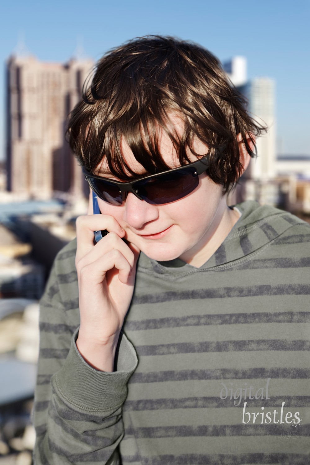 Teenage boy talking on the phone from a rooftop with a city view