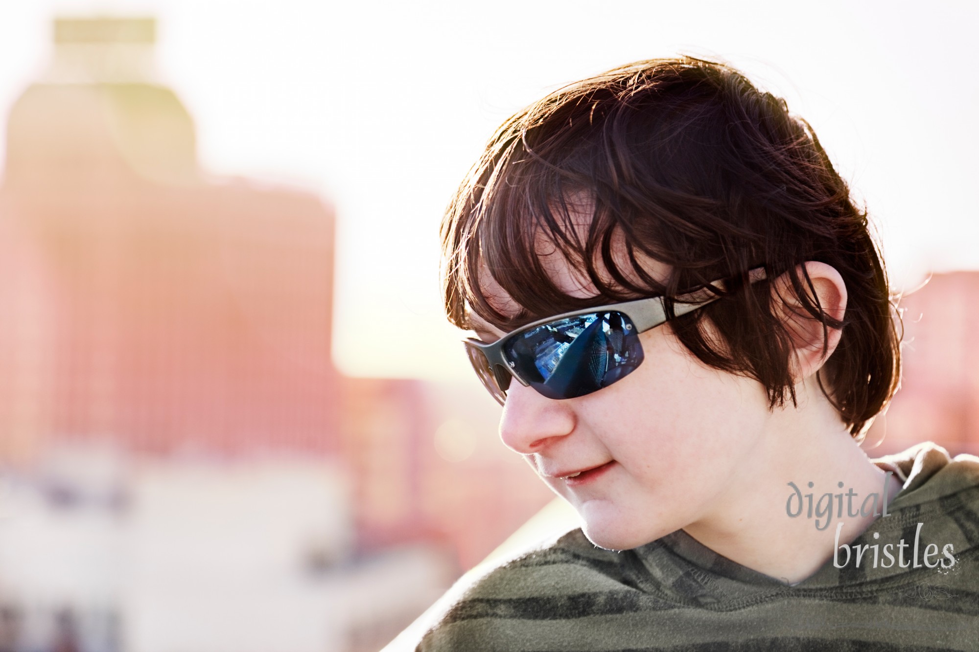 Teenage boy looks down at the city from a rooftop deck