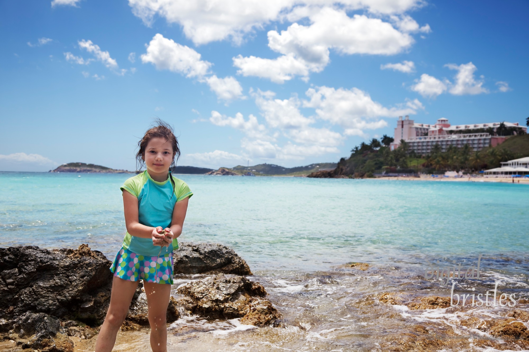 Young girl scoops sand and shells from a tide pool