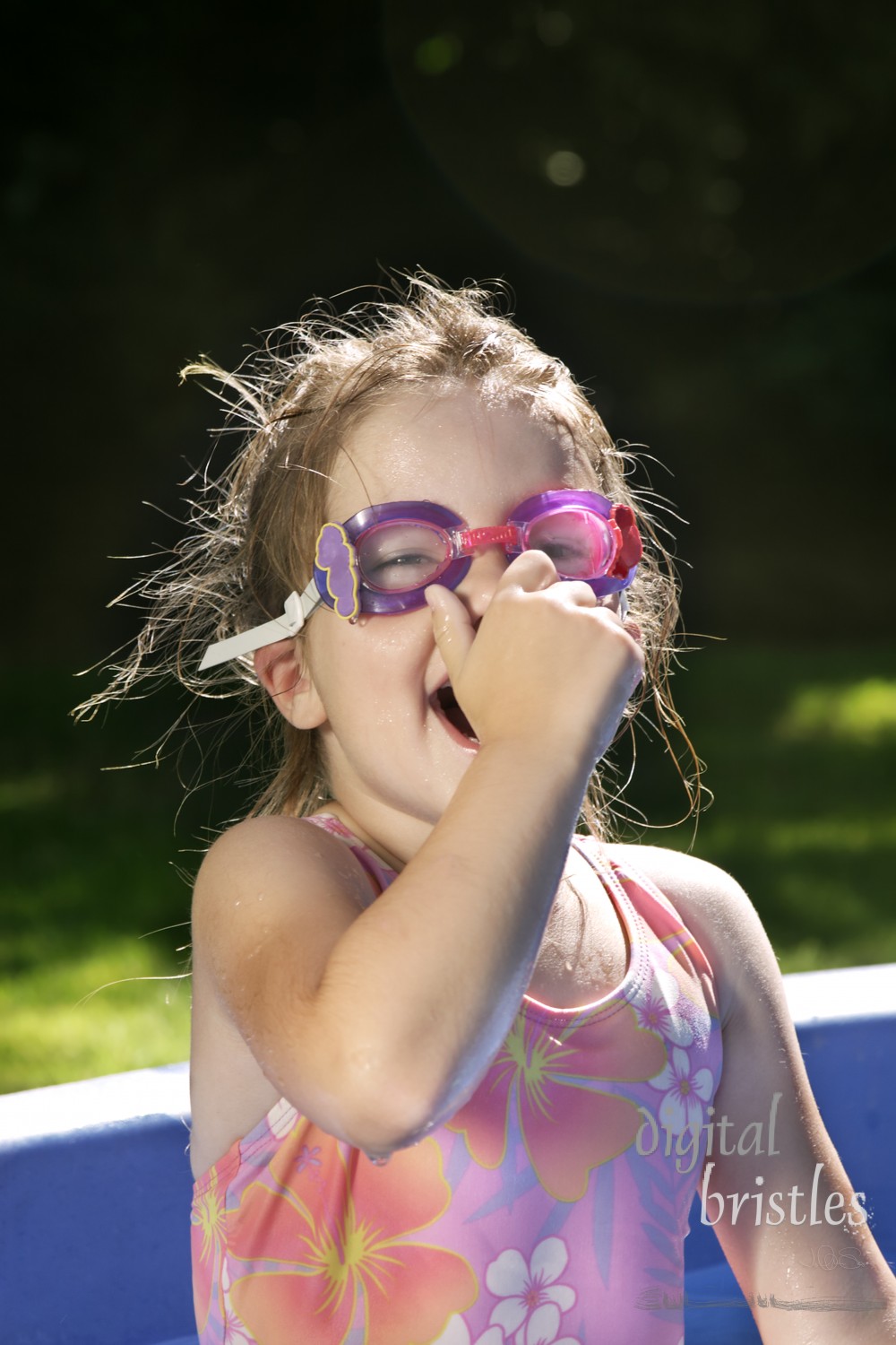 Young girl smiles holds her nose, ready to try new swim goggles