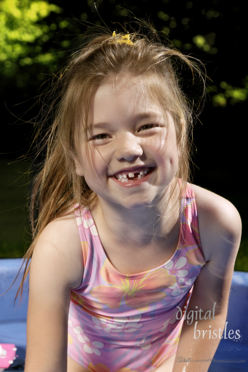 Young girl happy to be in the paddling pool on a summer day