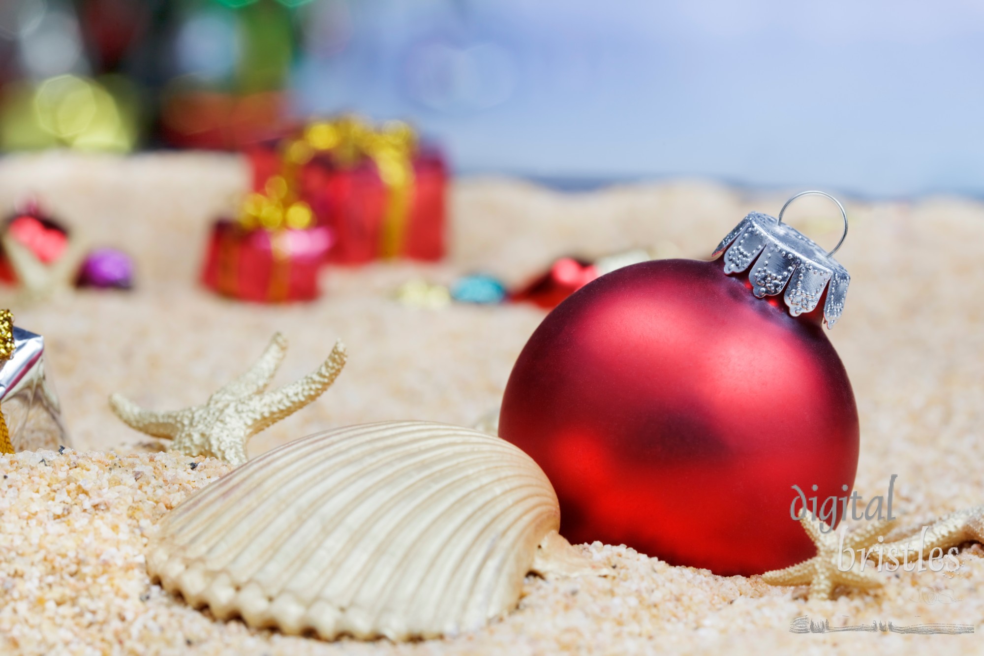 Red Christmas ornaments and shells in the sand