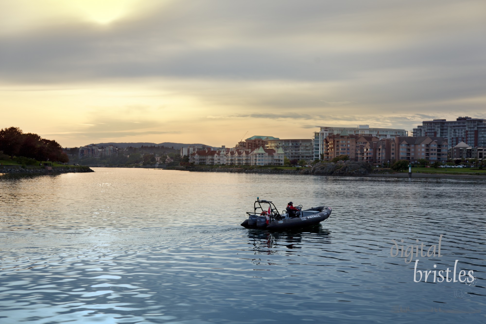 Transport Canada patrol boat crossing Victoria's Inner Harbour near sunset, heading for the Upper Harbour. Transport Canada helps ensure the safe operation of commercial shipping and passenger vessels in this busy British Columbia port