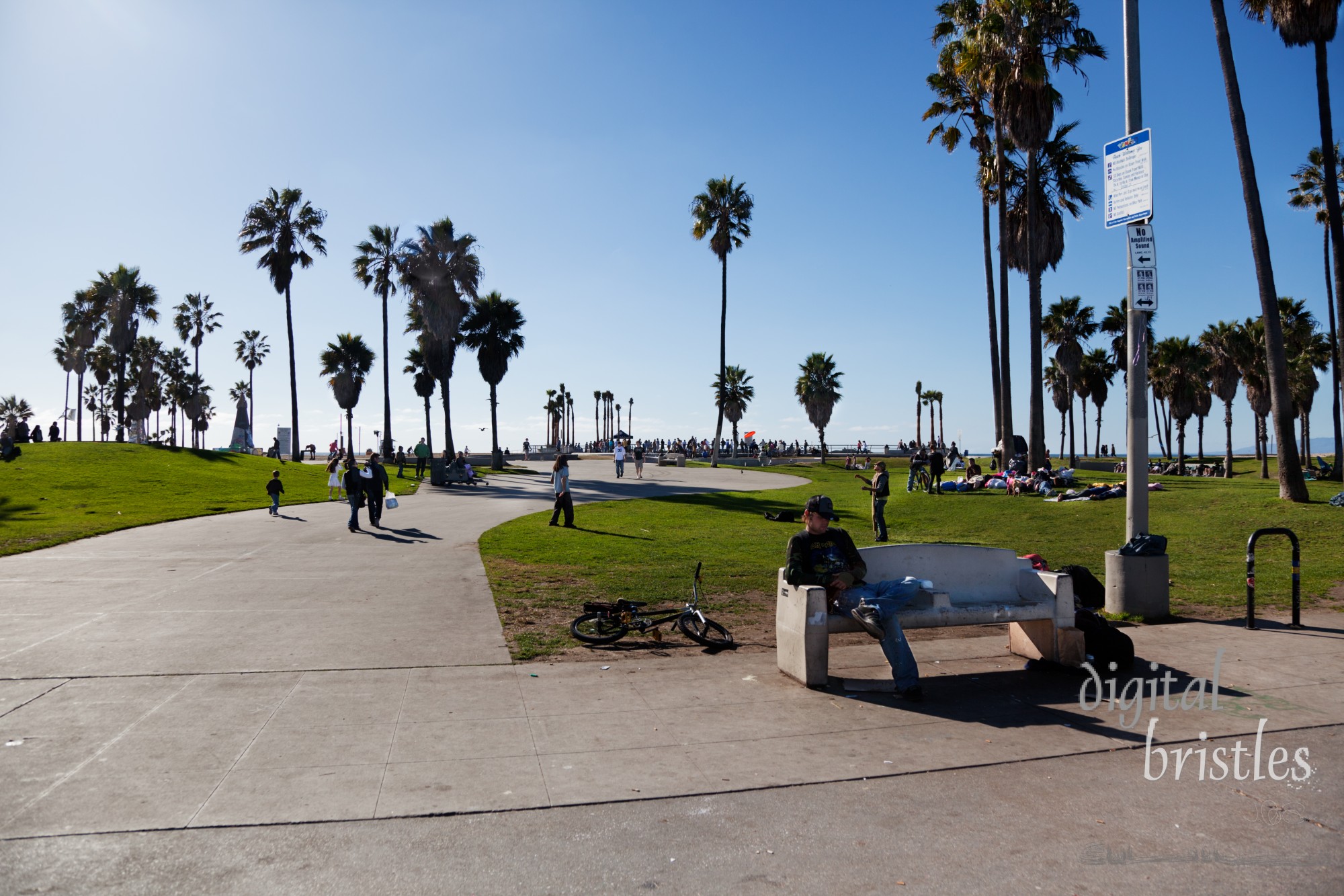 The Boardwalk on Venice Beach looking toward the ocean. A popular tourist destination, Venice Beach also has a substantial homeless population, some of whom use the park between the boardwalk and the beach.