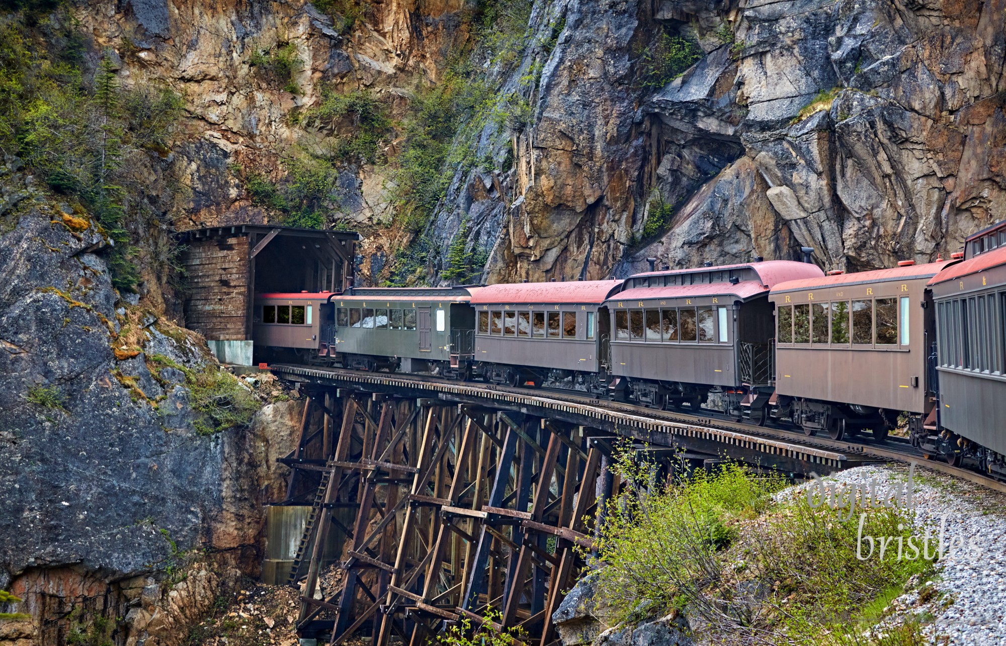 Historic narrow gauge railroad from Skagway, Alaska to White Pass goes from wooden trestle to a wood- lined tunnel entrance