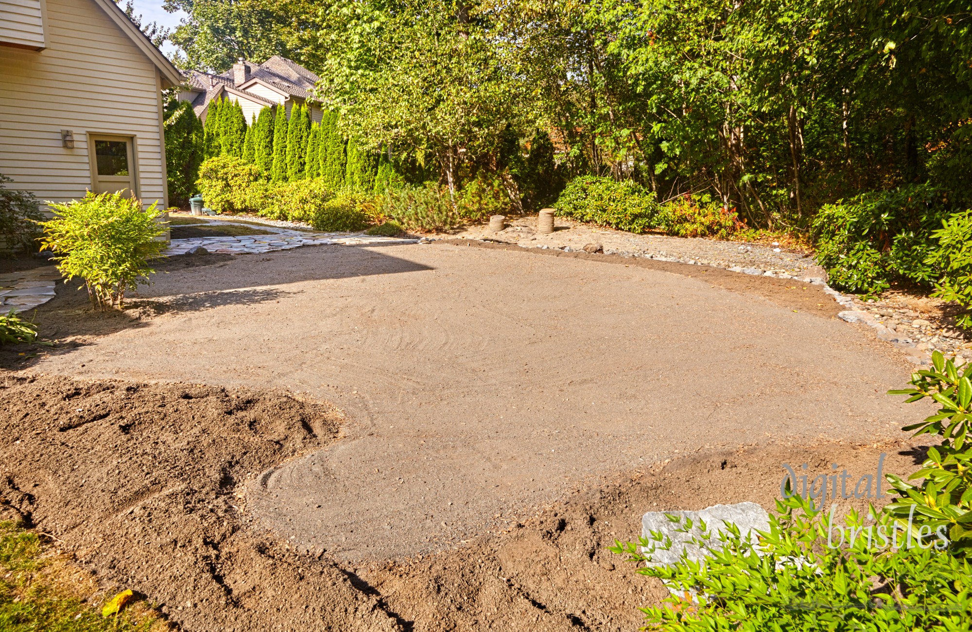 Curved edges where the patio stones will go are marked loosely against the flowerbed and its potting soil