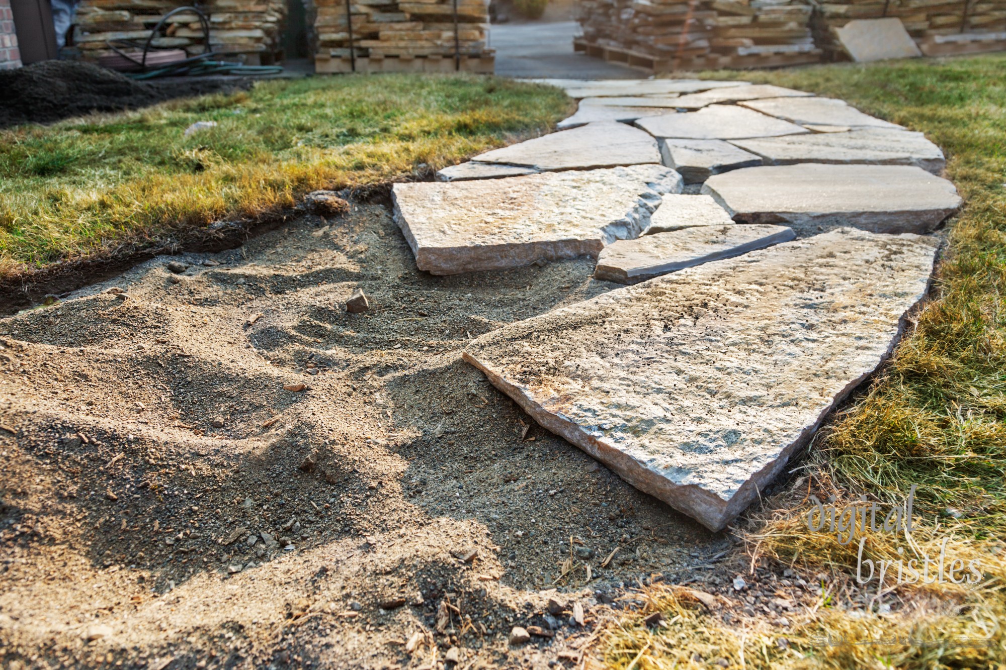 Stone path beginning with piles of pavers in the background