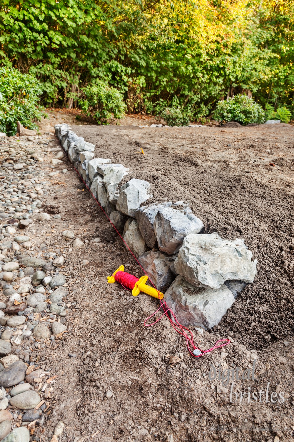 A low stone retaining wall to hold in gravel, sand and dirt for patio area