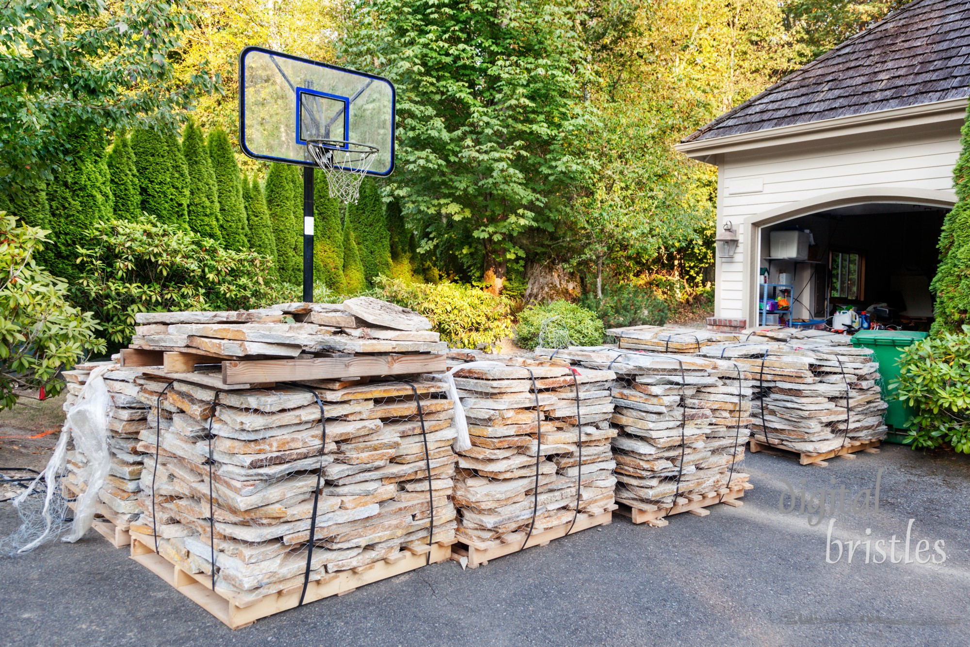 Pallets of paving stones, secured with wire and straps, sit in the driveway