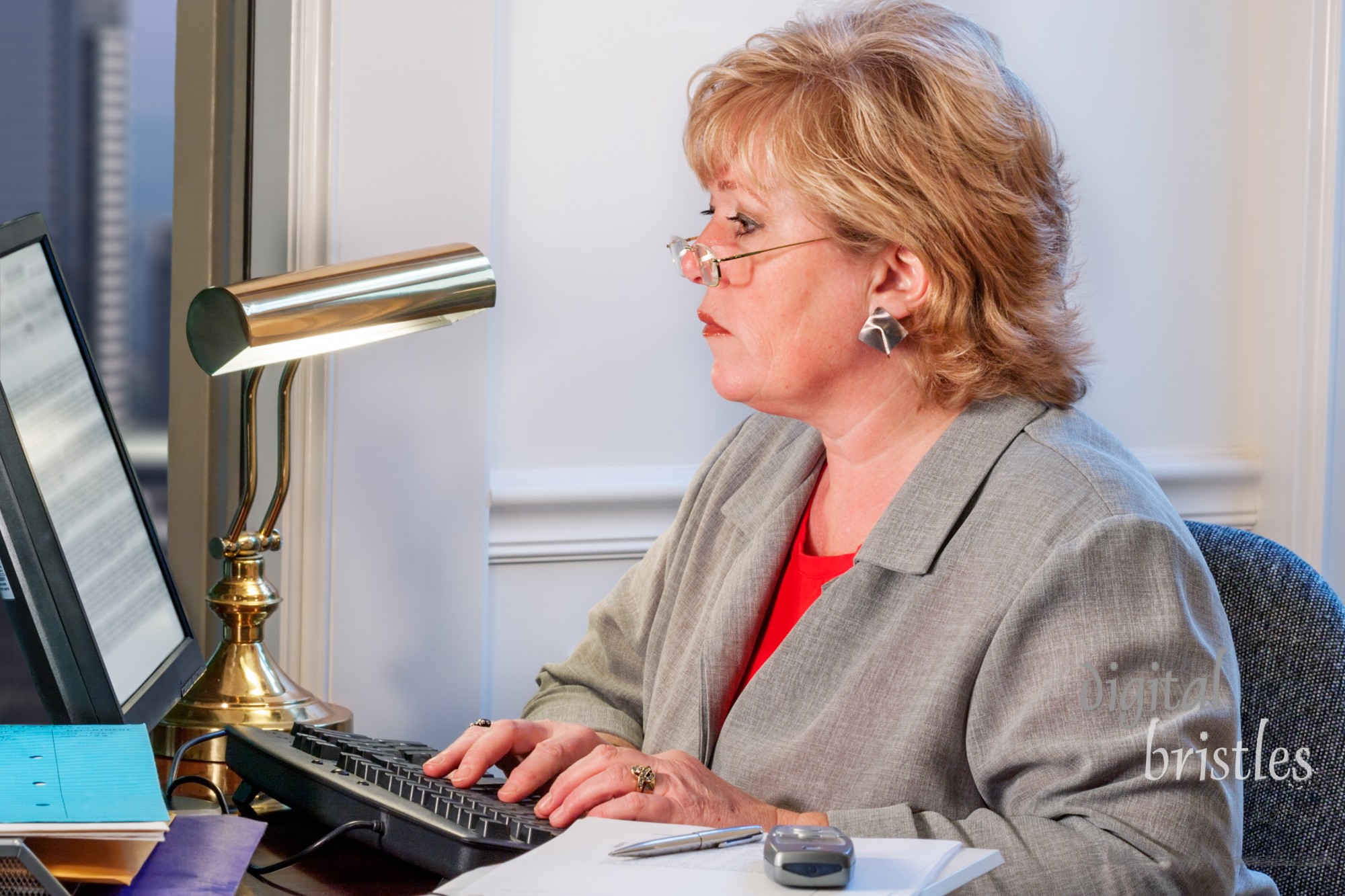 Mature businesswoman typing and working at her desk. Clipping path for monitor interior