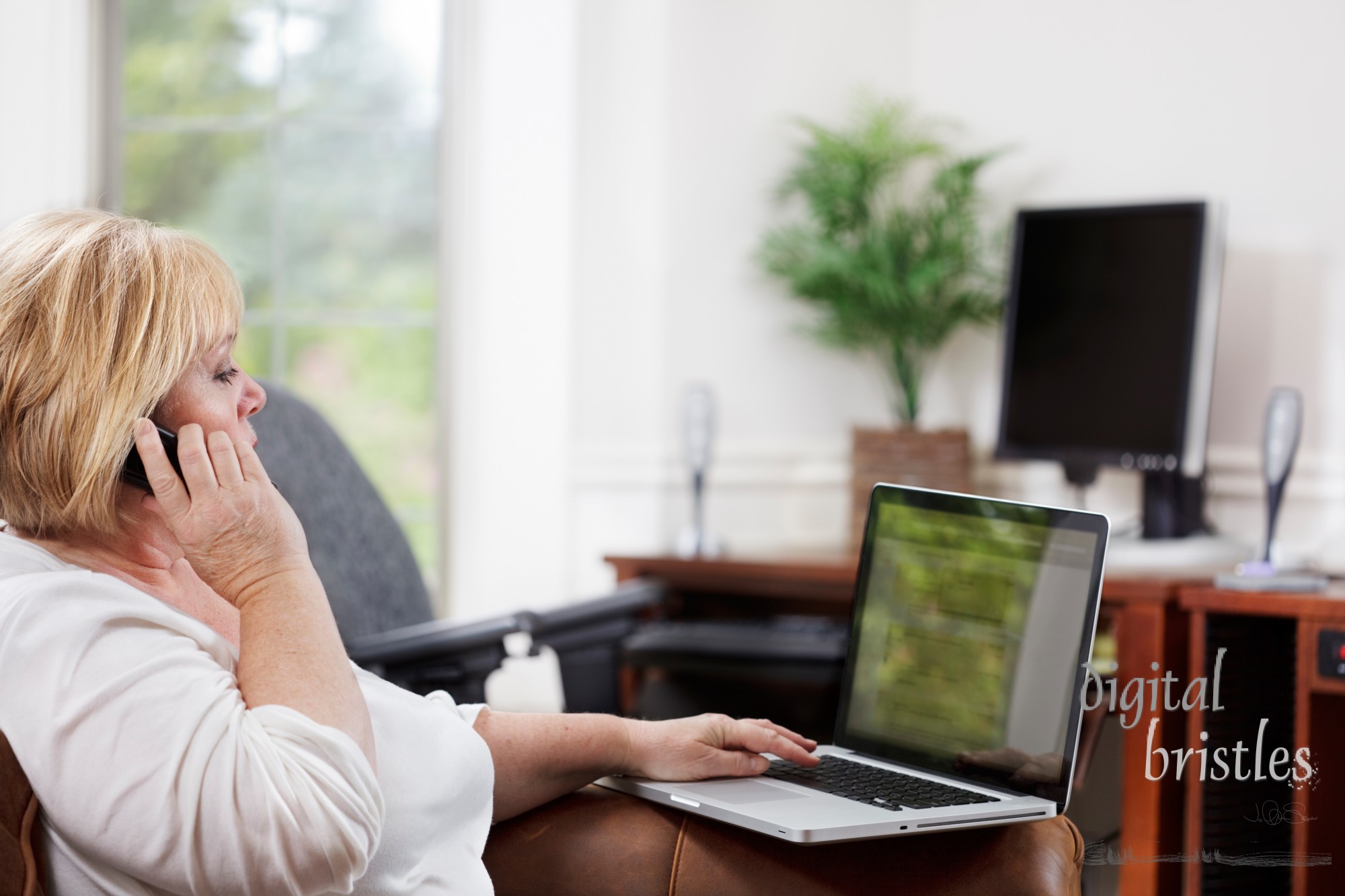 Mature woman on the phone with laptop in home office