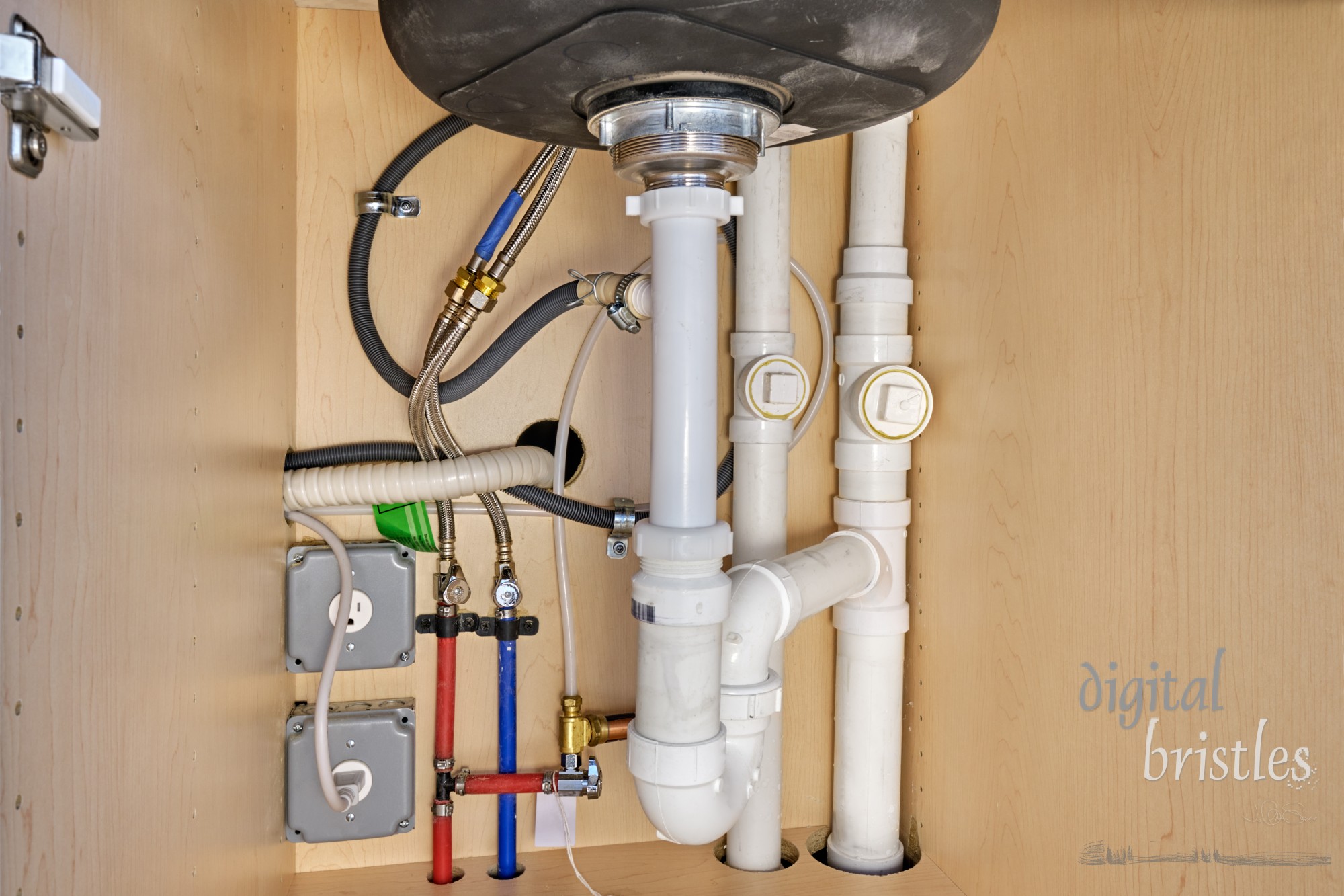 Pipes and electrical in a residential kitchen under the sink