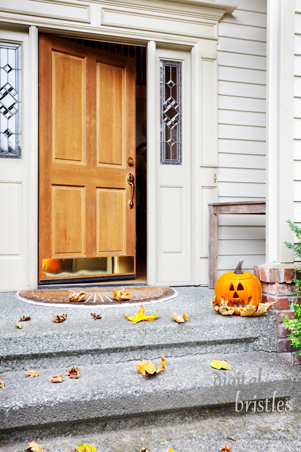 Front steps and open front door with fall leaves and jack-o-lantern