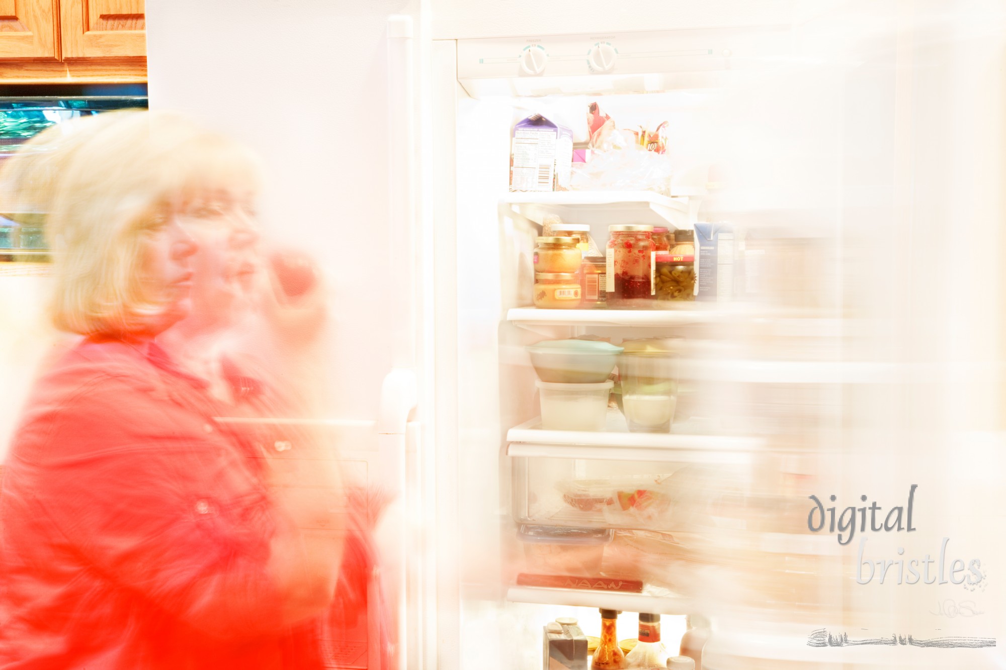 Woman busily moving about - getting  a healthy snack (apple) out of the refrigerator