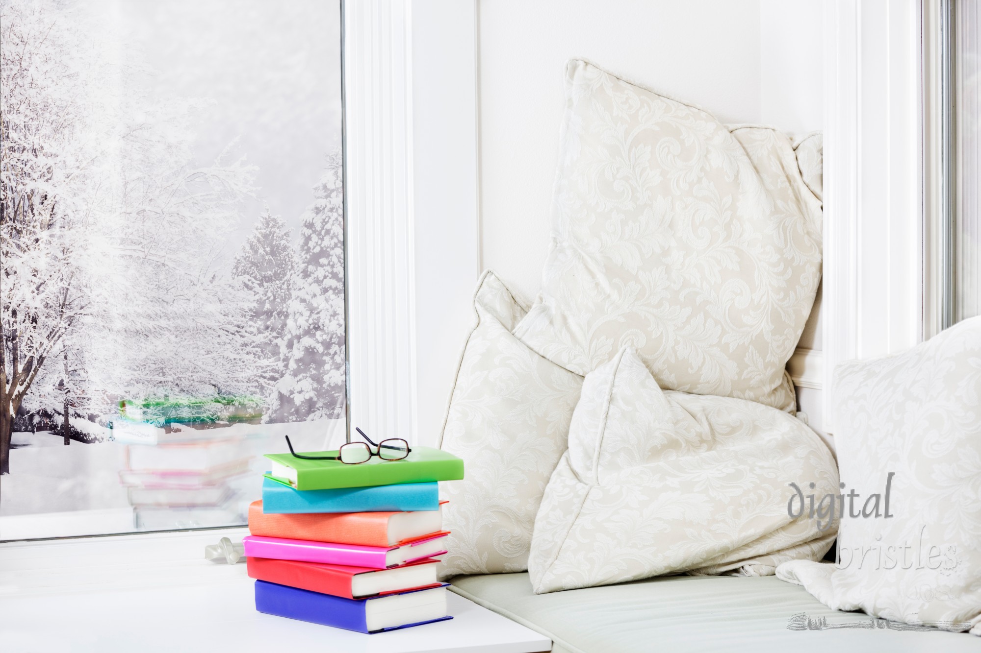 Window seat with comfy cushions and a stack of books