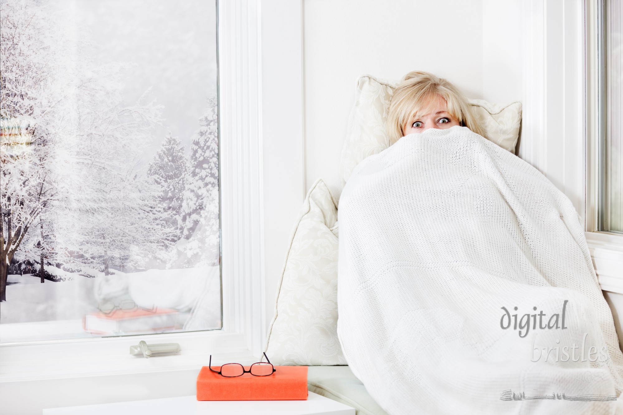 Mature woman lying down & peeking out from a warm blanket