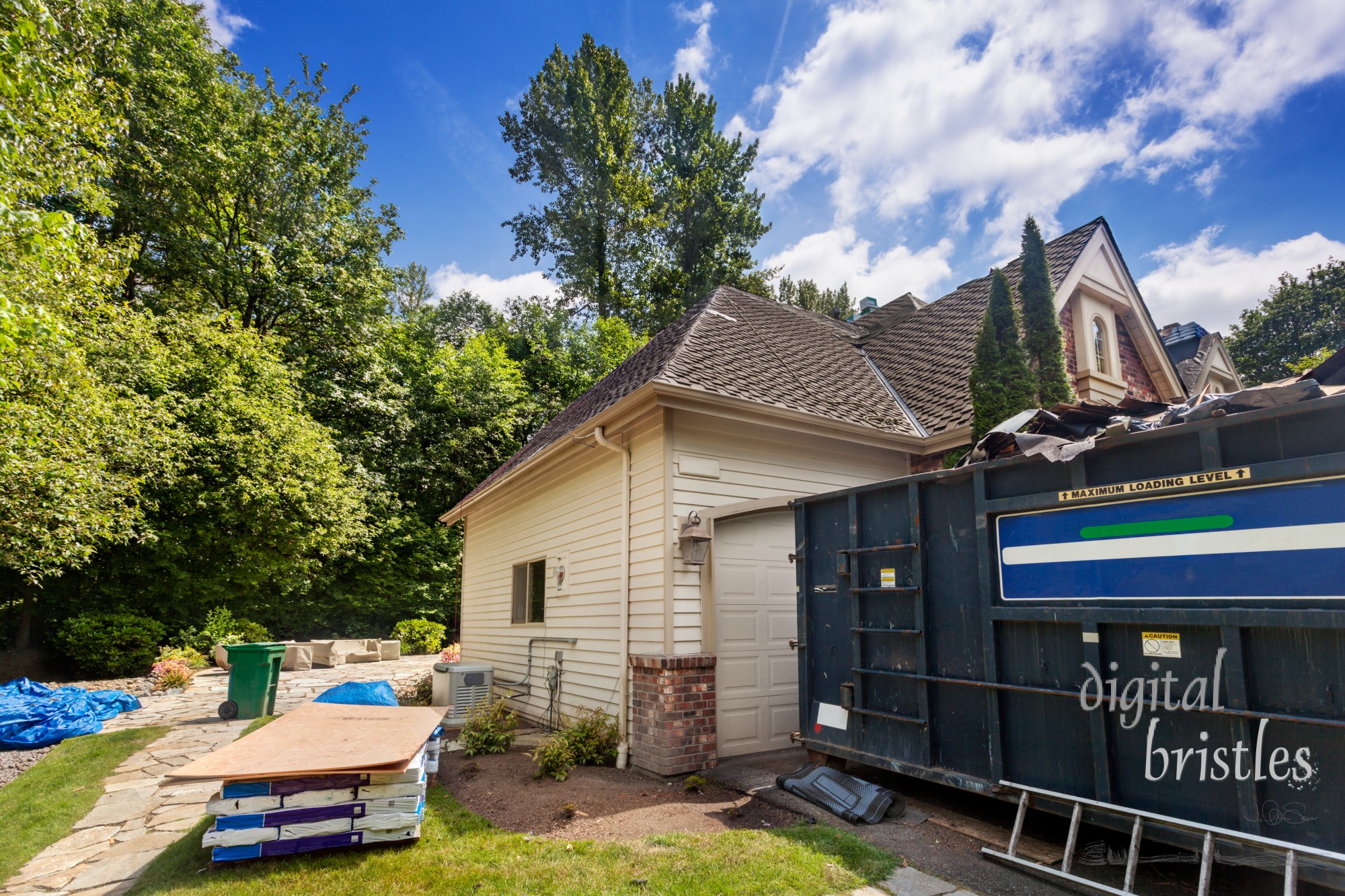 Suburban home in the middle of a re-roofing project, with new shingles and plywood waiting to be installed and dumpster to contain the debris