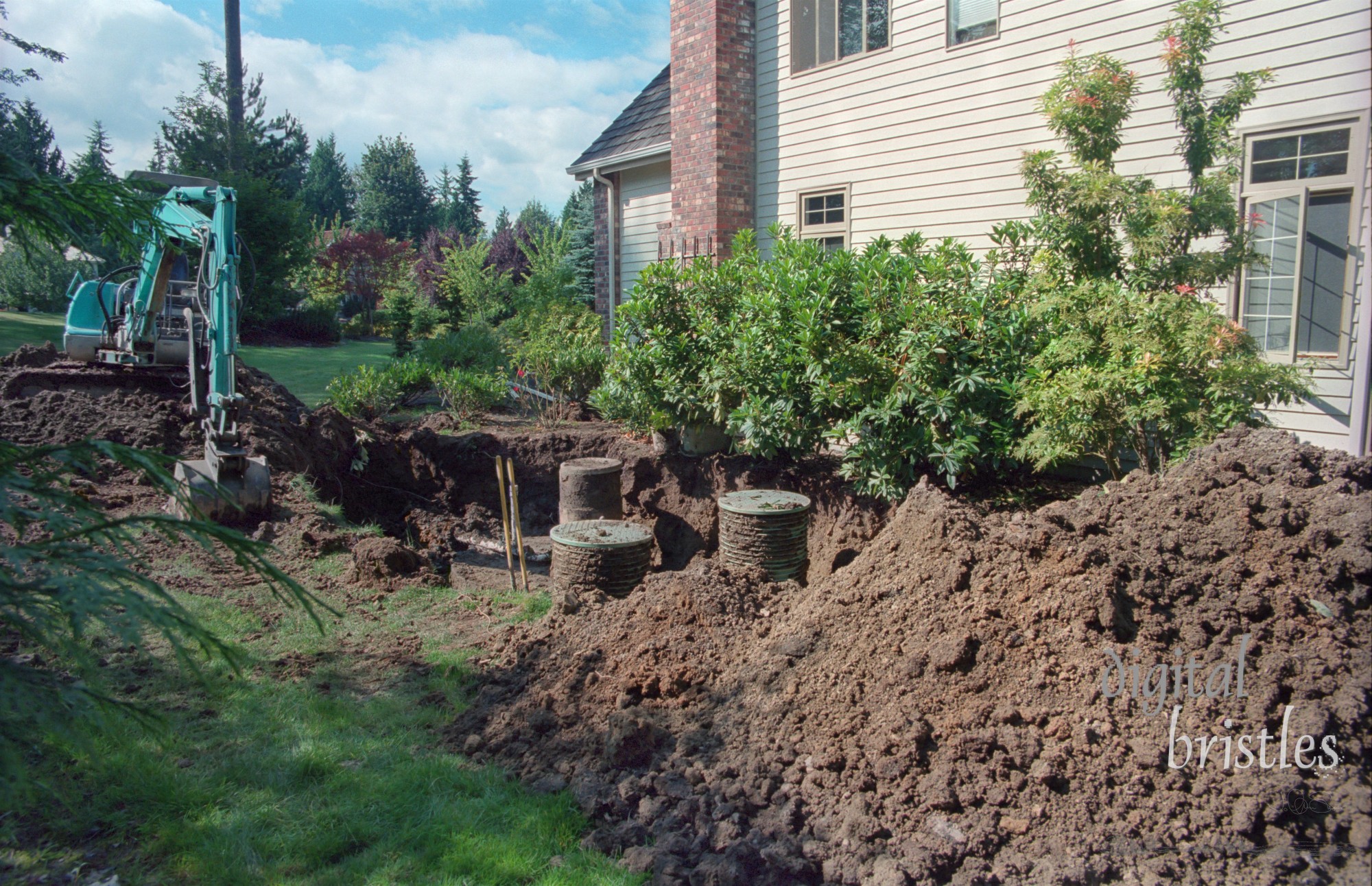 Digging out residential septic tanks with an excavator, preparing for maintenance work. Note: scan from 35mm film