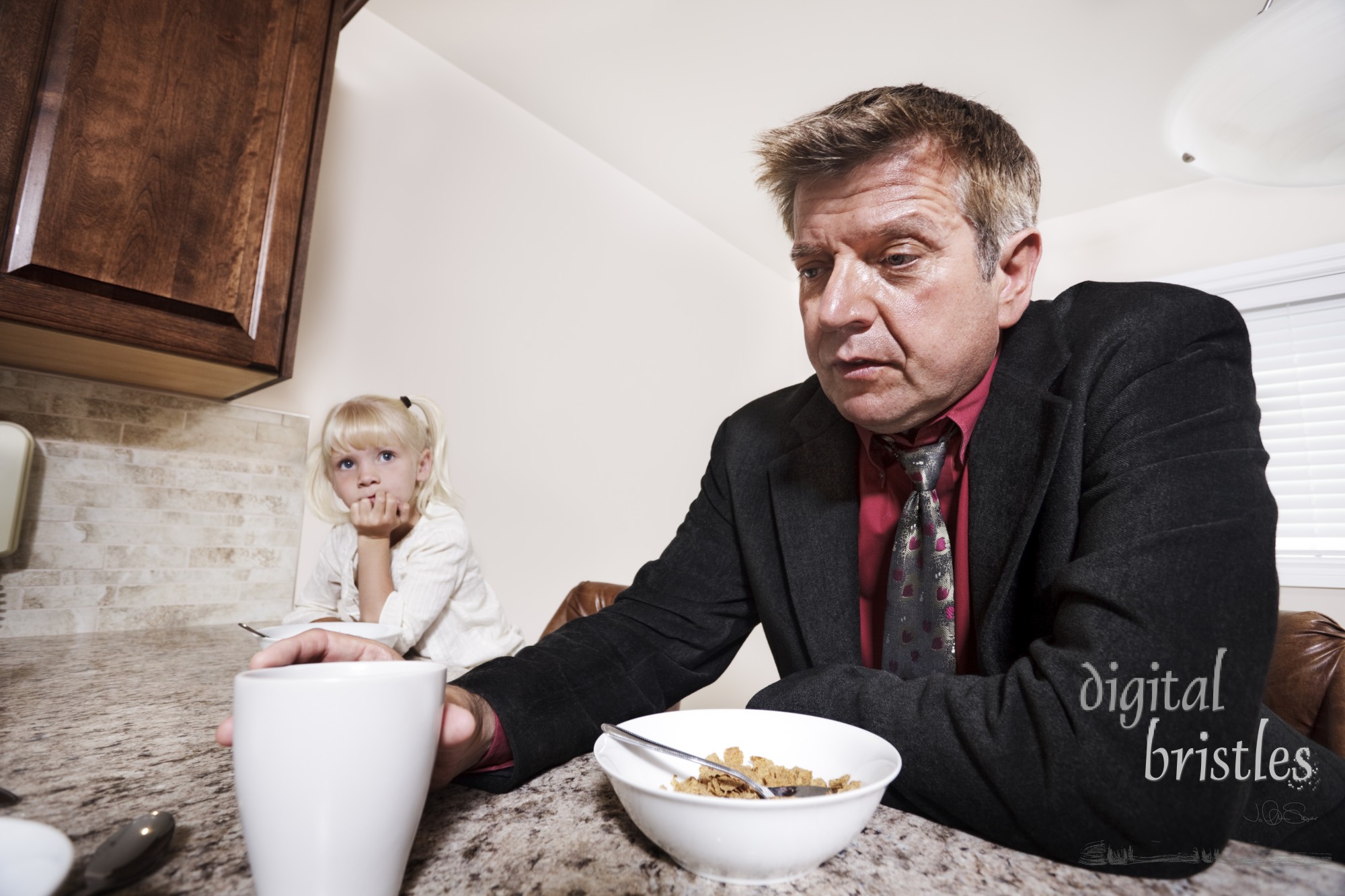 Dad sits and worries as he eats breakfast