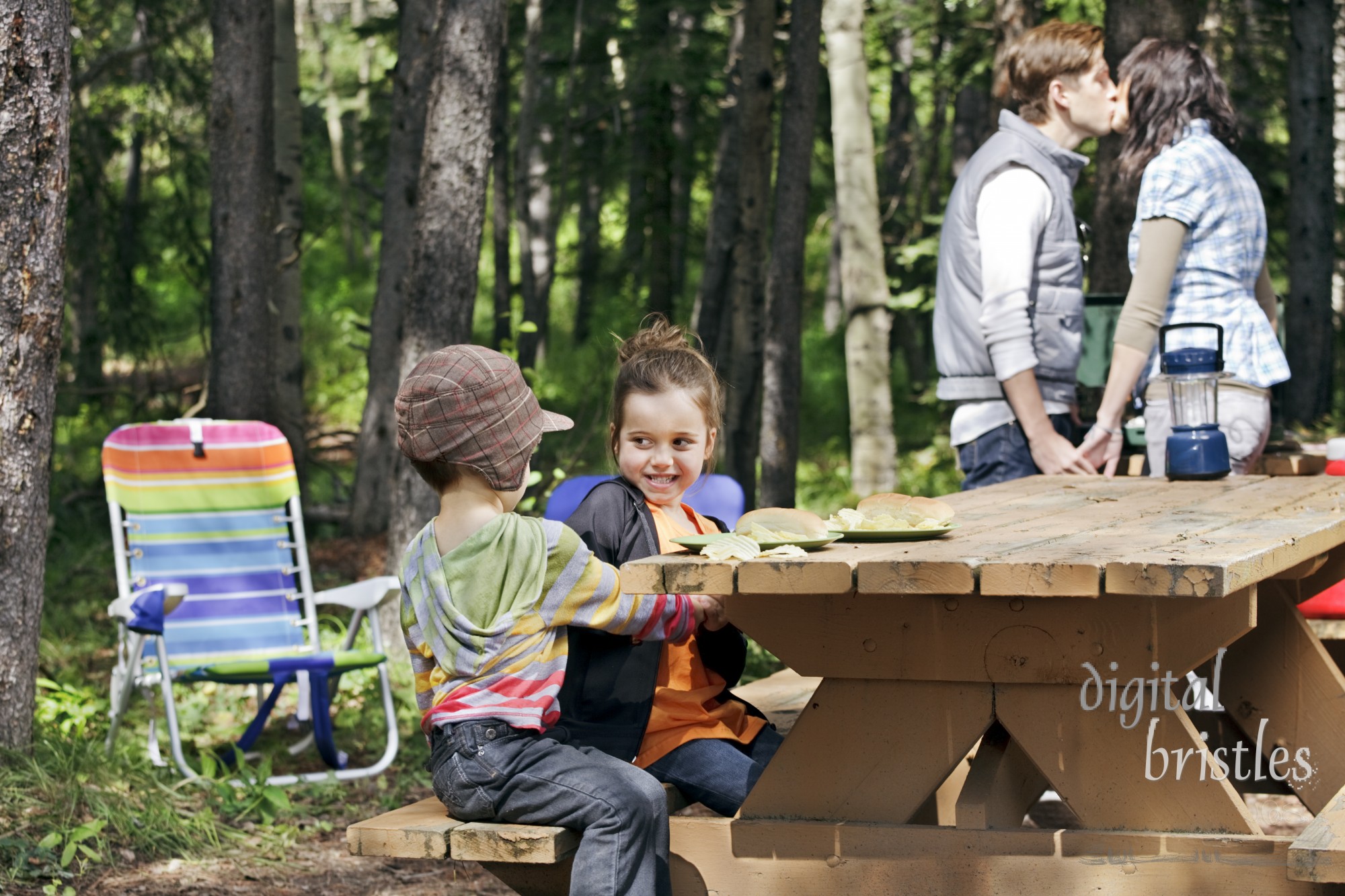 Kids fight while Mom & Dad steal a kiss over the camp stove