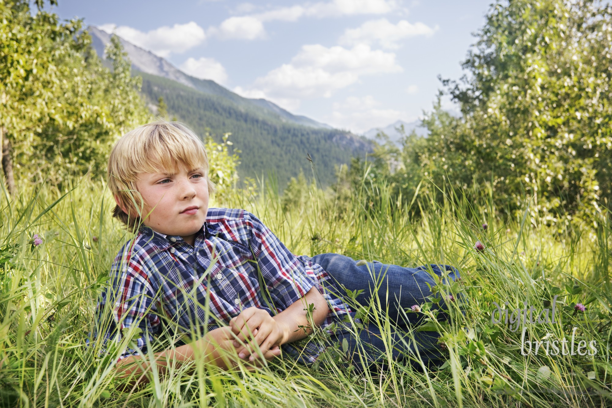 Little boy lies in a grassy mountain meadow to think