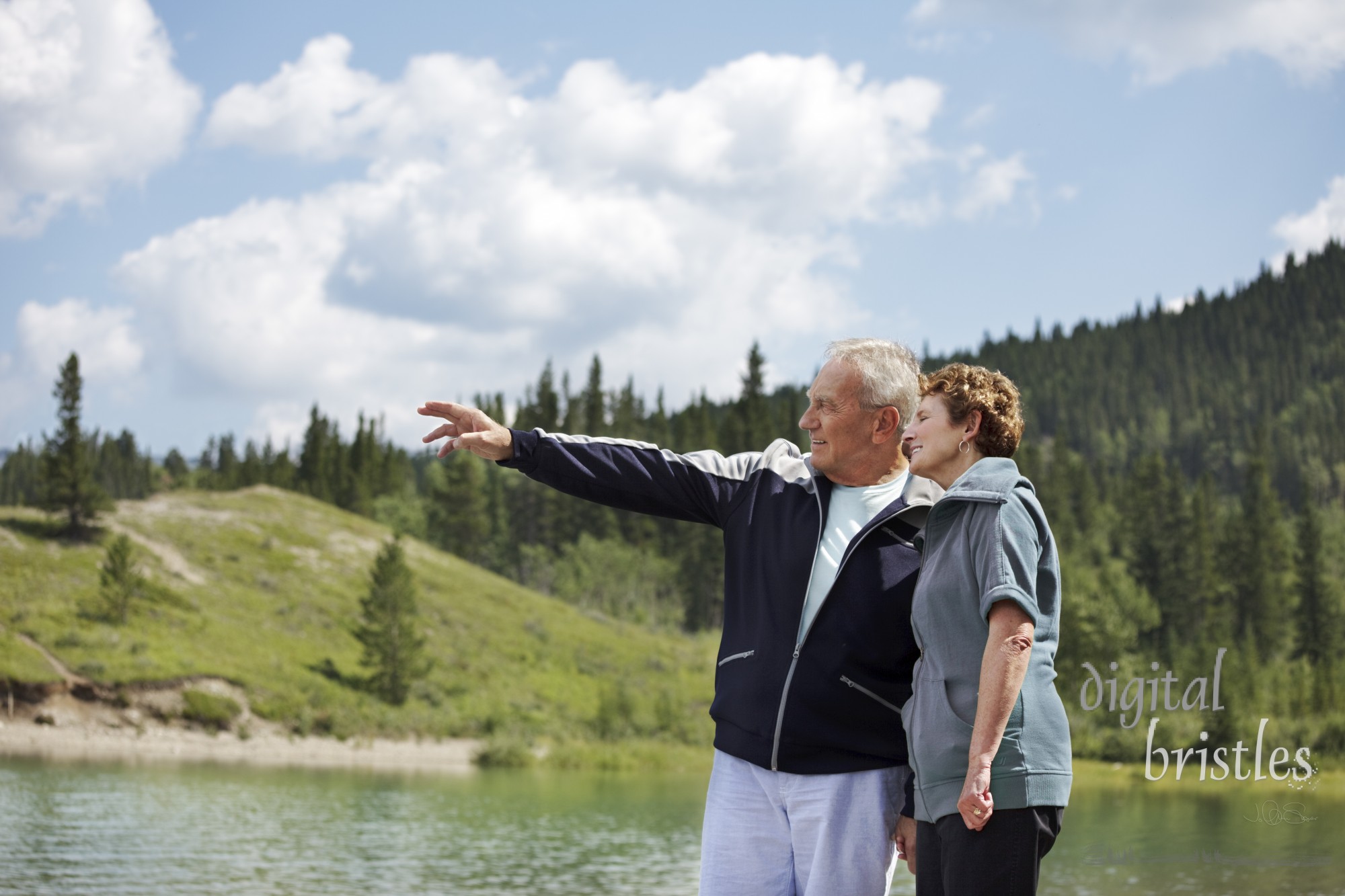 Senior couple walking by the lake, husband pointing out into the distance