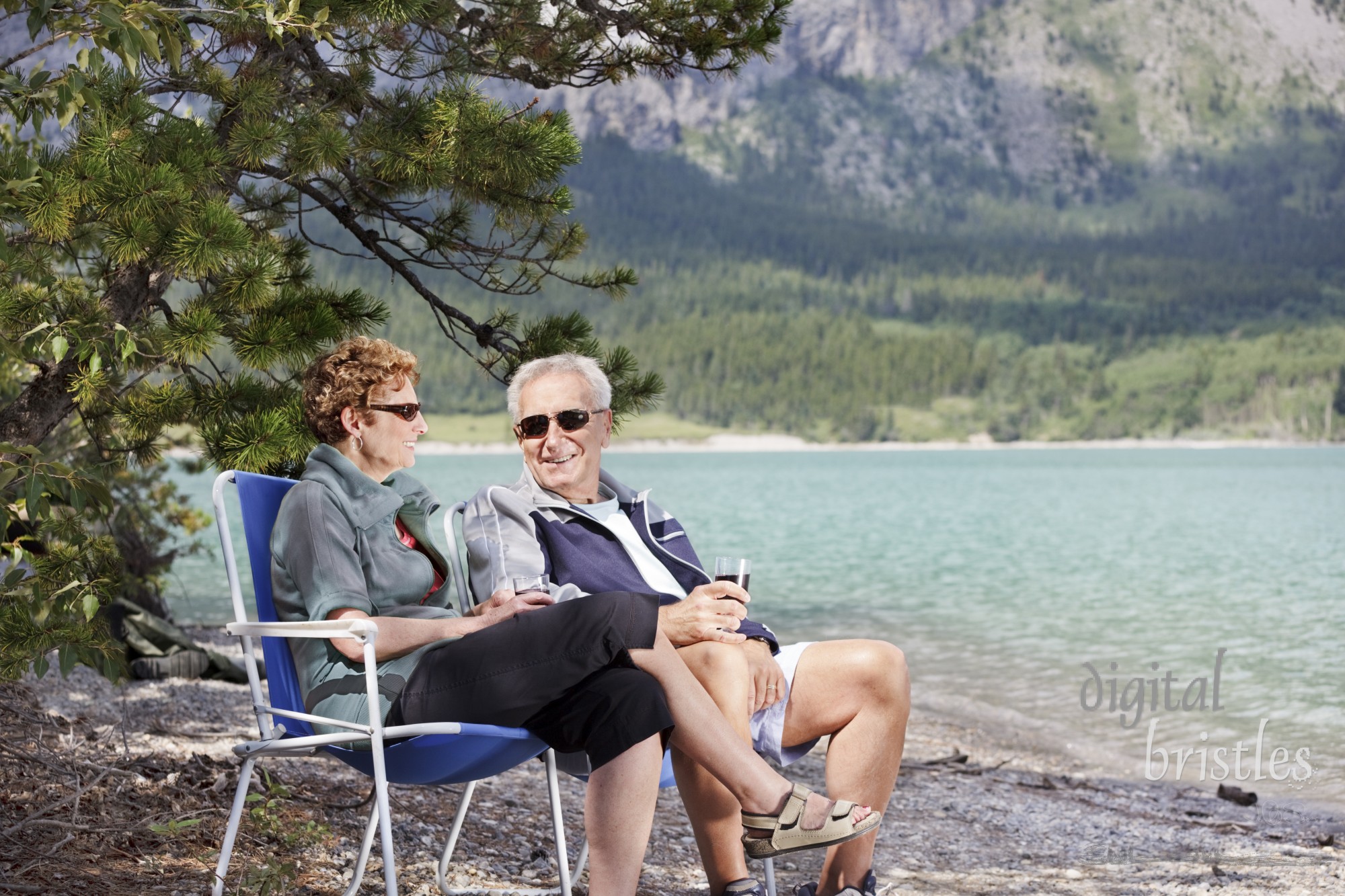 Senior couple sit with a glass of wine by a mountain lake